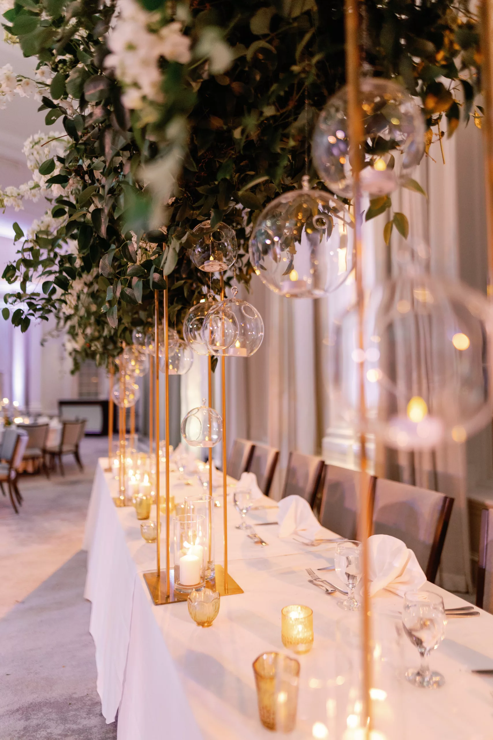 Luxurious White and Gold Grand Ballroom Wedding Reception Head Table Decor Ideas | Hanging Glass Vase Globe Tealight Candle Holder, Long White Feasting Table, Tall Gold Floral Stand with Cascading Greenery and White Flowers | Tampa Bay Event Planner Coastal Coordinating