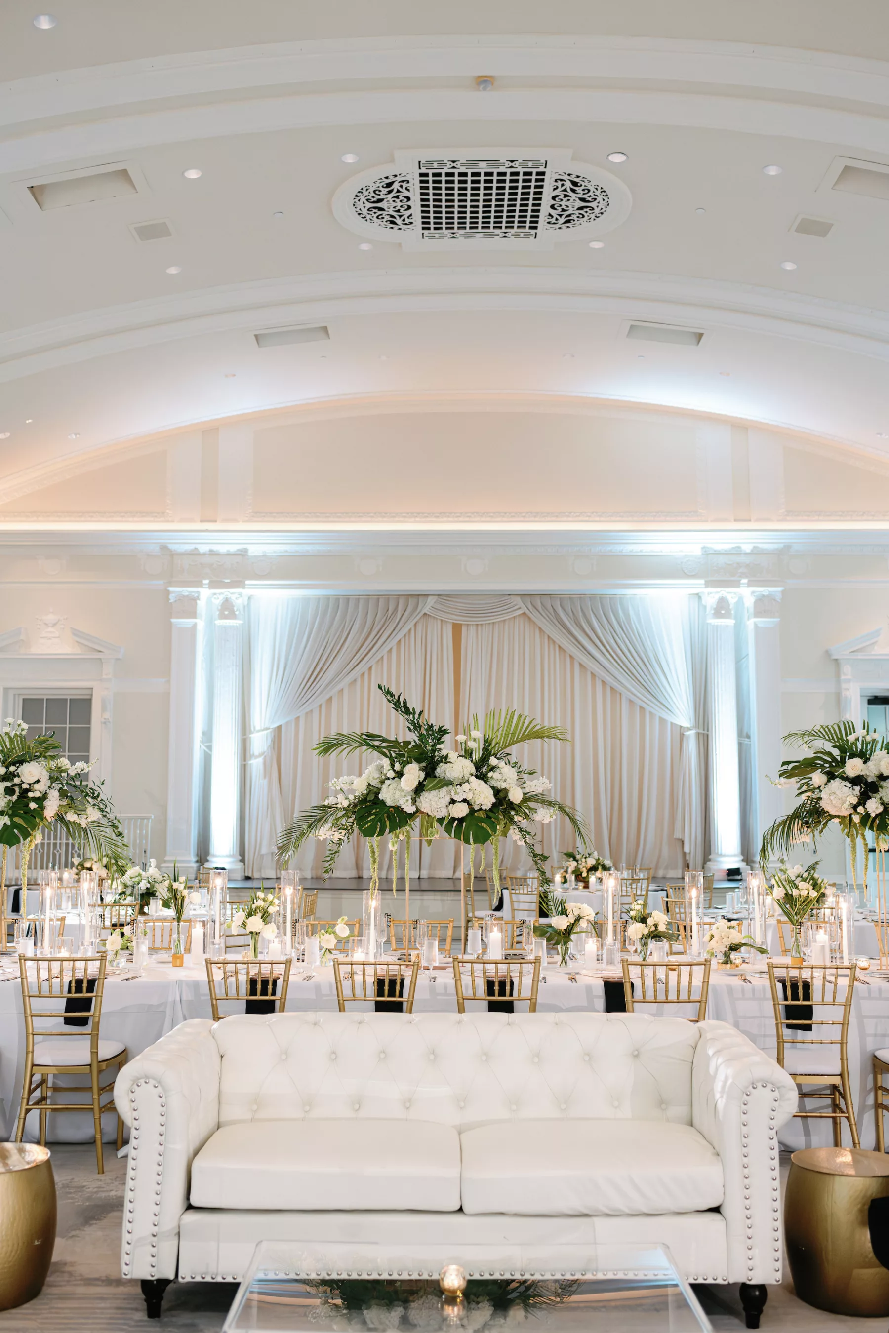 Modern Timeless White and Gold Ballroom Wedding Reception Ideas | White Tufted Couch Lounge Furniture Inspiration | Tropical Centerpiece Decor | Monstera Leaf, White Hydrangeas and Roses Floral Arrangement | Tampa Bay Event Planner Coastal Coordinating | St Pete Florist Botanica Design Studio