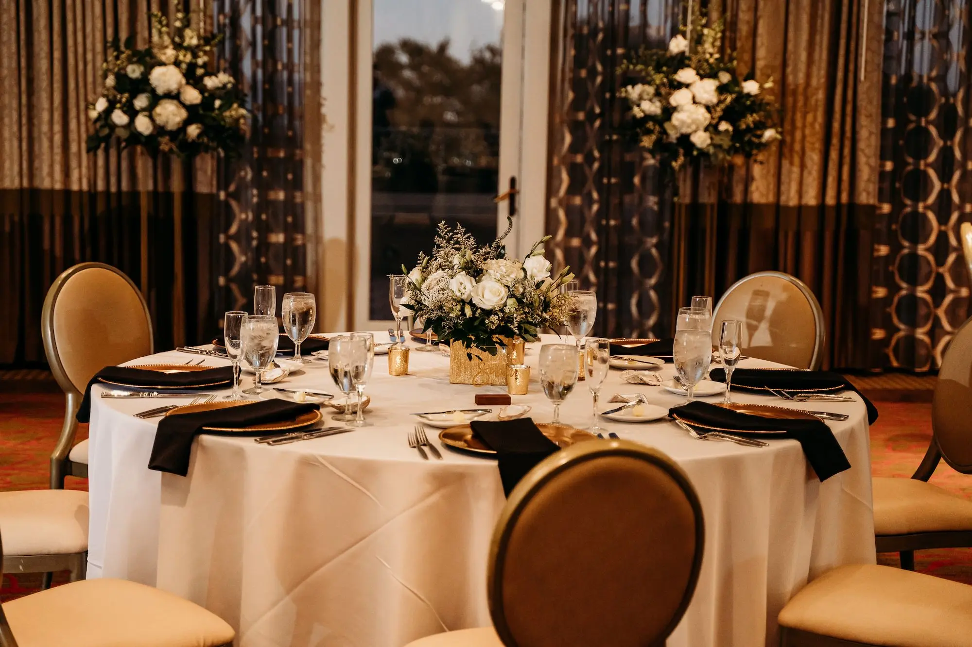 Luxurious Fall Grand Ballroom Wedding Reception Tablescape Inspiration | Gold Mercury Bud Vases with White Hydrangeas, Roses, and Greenery Centerpiece Ideas | Gold Chargers with Black Linen Napkins