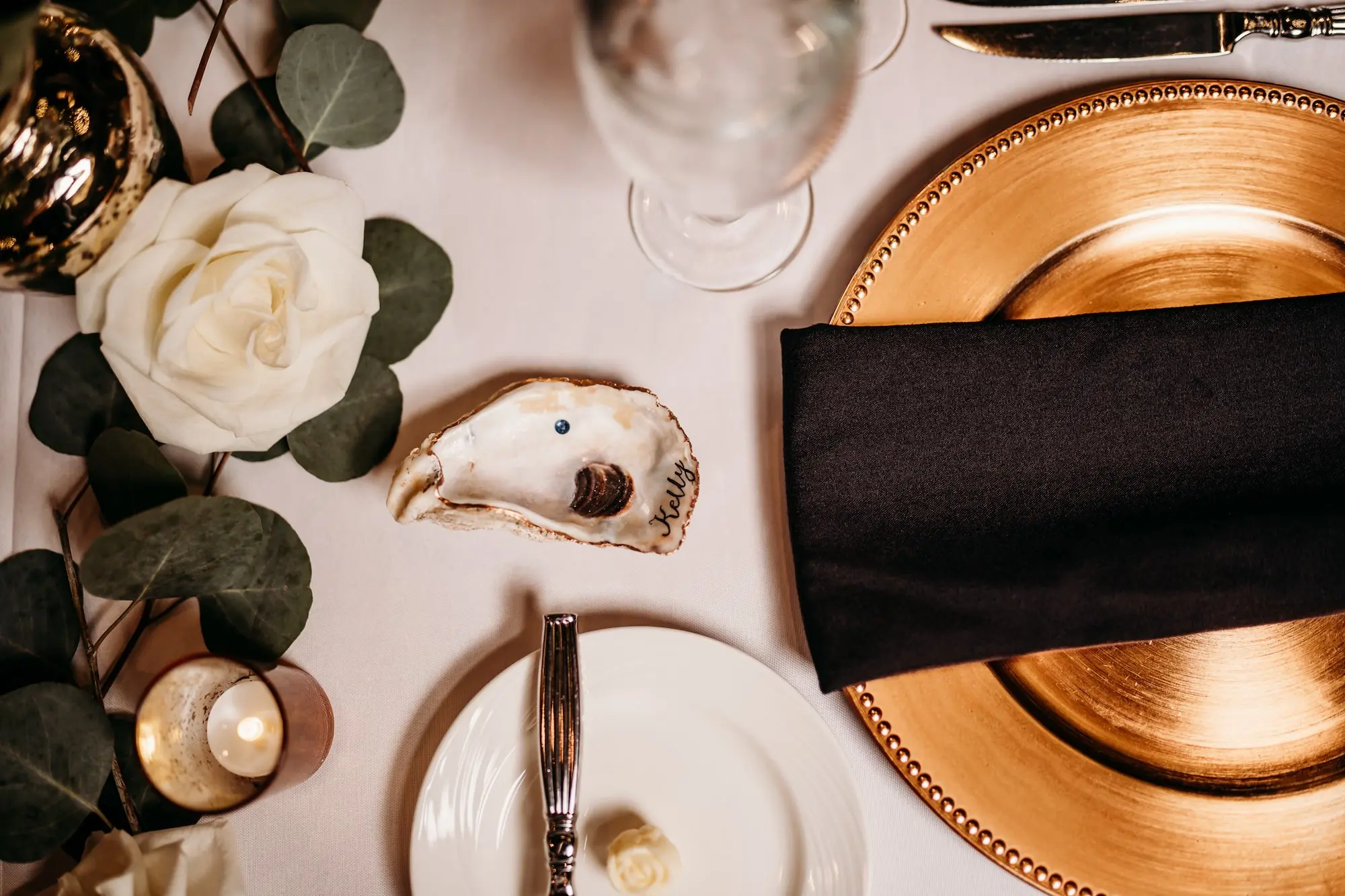 Elegant Wedding Reception Black and Gold Place Setting with Oyster Place Card Ideas | White Florals and Greenery Garland Centerpiece Decor Inspiration | Calligrapher Inky Fingers Calligraphy
