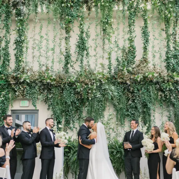 Bride and Groom First Kiss Wedding Ceremony Portrait | Modern Black and White with Lush Greenery Rooftop Wedding Ceremony Decor with Green Garland Hanging Backdrop Inspiration | Black Tie Wedding Inspiration | Tampa Bay Event Planner Coastal Coordinating | Downtown Venue The Edition Hotel