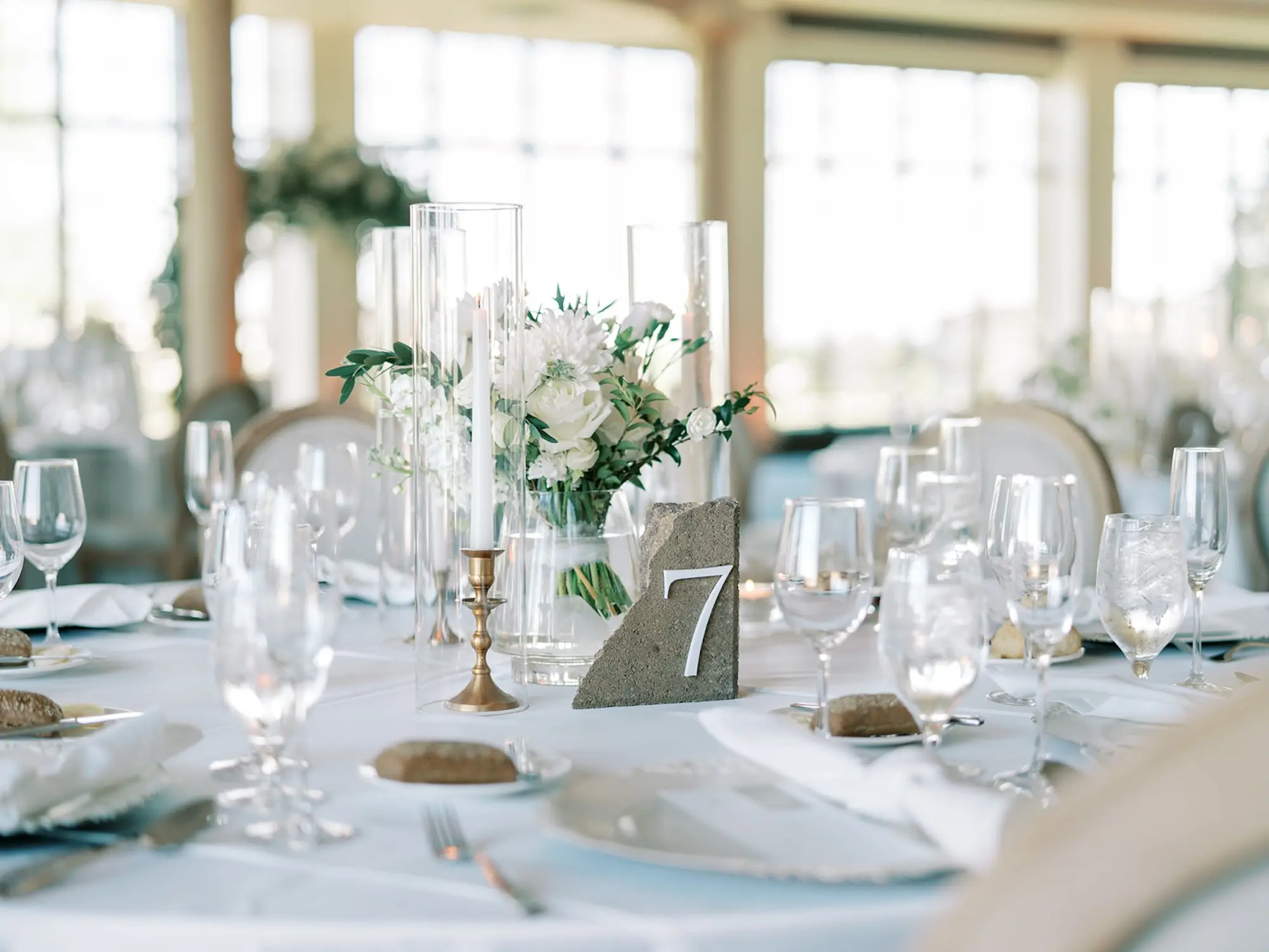Timeless Small Vases of White Roses and Hydrangea Stems WEdding Reception Centerpiece Inspiration | Gold Candle Vases with White Taper Candle Reception Decor Ideas | Spring Florida Wedding Inspiration | Natural Stone Reception Table Numbers Inspiration