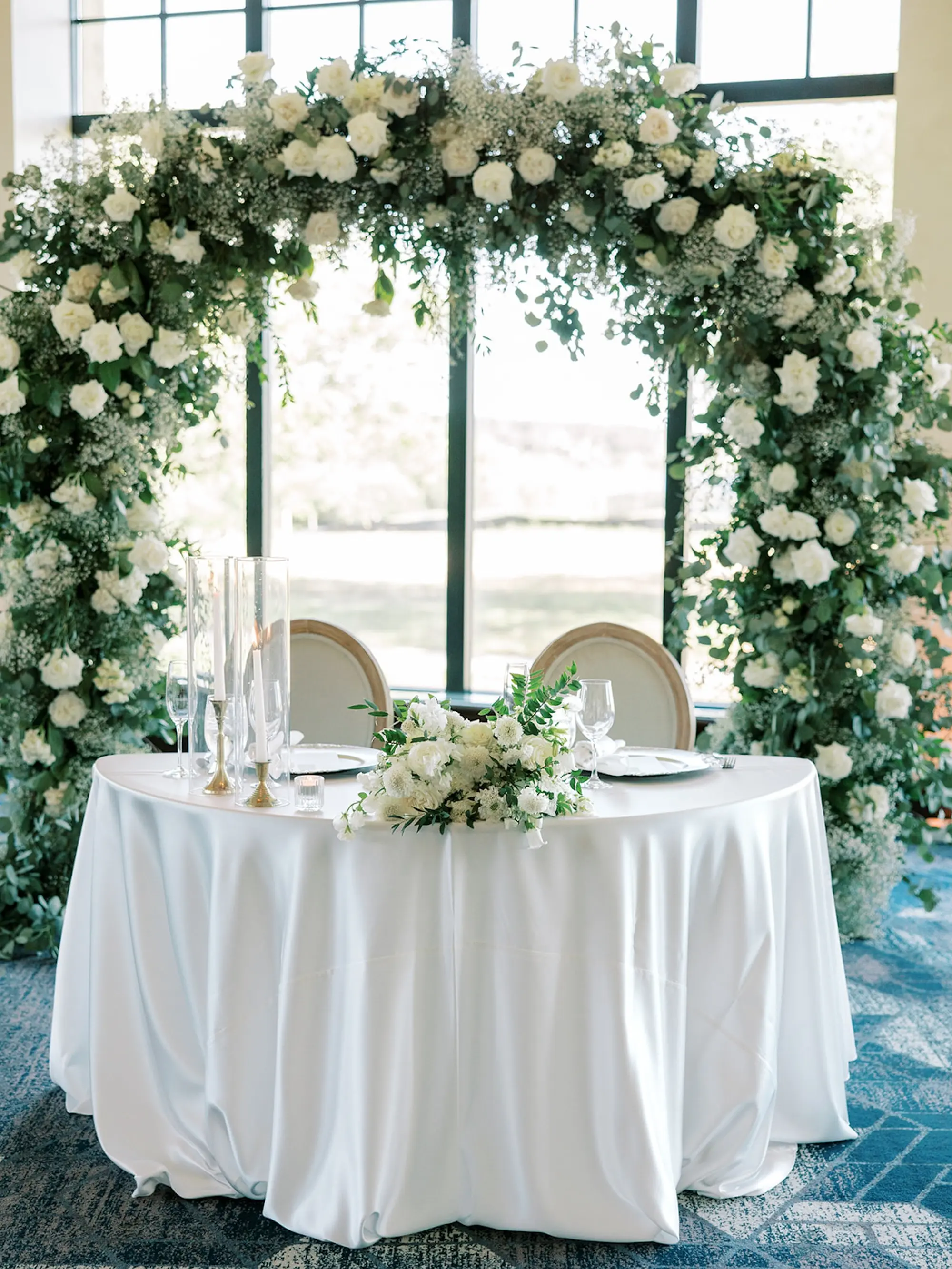 White Roses and Baby Breath Flower Arch Sweetheart Table Decoration Inspiration | Spring Florida Wedding Reception Decor Ideas | Timeless White Linens and Romantic Candlelight Reception Decor Inspiration