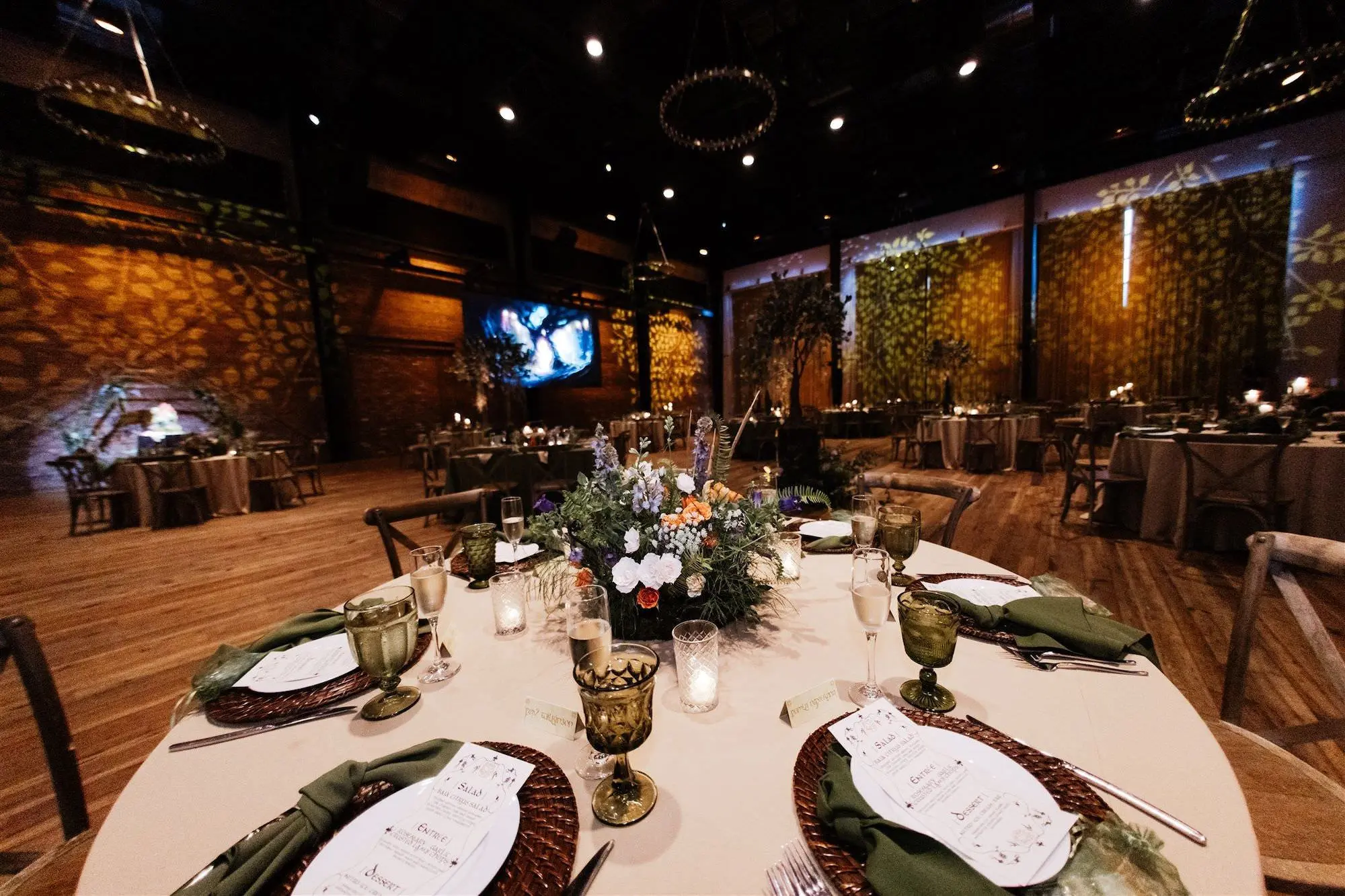Elegant Fantasy Ballroom Lord of the Rings Wedding Reception Tablescape Place Setting Decor Ideas | Brown Wicker Chargers with White Menu Cards and Olive Green Napkin Inspiration | Green Depression Glass on White Linens with Small Lush White, Pink, Orange and Purple Floral Arrangement Reception Table Decor Ideas | Downtown Tampa Event Venue Armature Works | Kate Ryan Event Rentals | Wooden Chair Rentals A Chair Affair | Planner UNIQUE Weddings and Events | Tampa Bay Over The Top Rental Linens