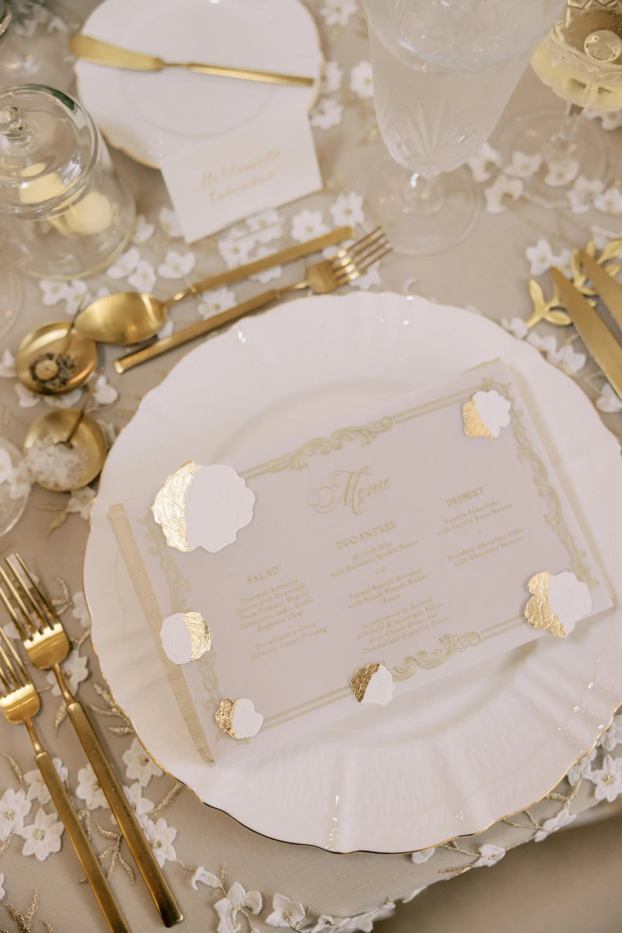 Luxurious Ivory and Gold Wedding Reception Place Setting Decor Inspiration | White Ridged Charger on White and Gold Floral Detailed Linens with Gold Flatware and Acrylic Menus with Gold Writing Tablescape Decor Ideas | Tampa Bay Event Planner Parties A La Carte
