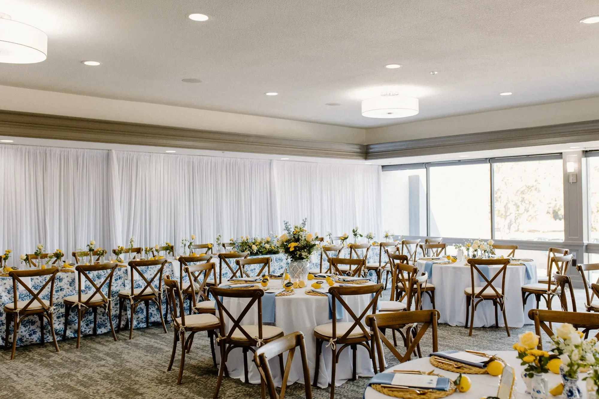 Blue and White Garden Rose Linen at Long Head Table and Wooden Chairs Wedding Reception Decor Inspiration | Lemon Citrus Garden Theme Wedding Reception Decor Ideas | Bud Vase with White and Yellow Rose Single Stem Centerpieces Inspiration | Blue and White Detailed Large China Vase with White Florals and Yellow Roses Centerpieces Inspiration | Tampa Bay Over The Top Linen Rentals | St Pete Rental A Chair Affair | Tampa Bay Planner Unique Weddings and Events