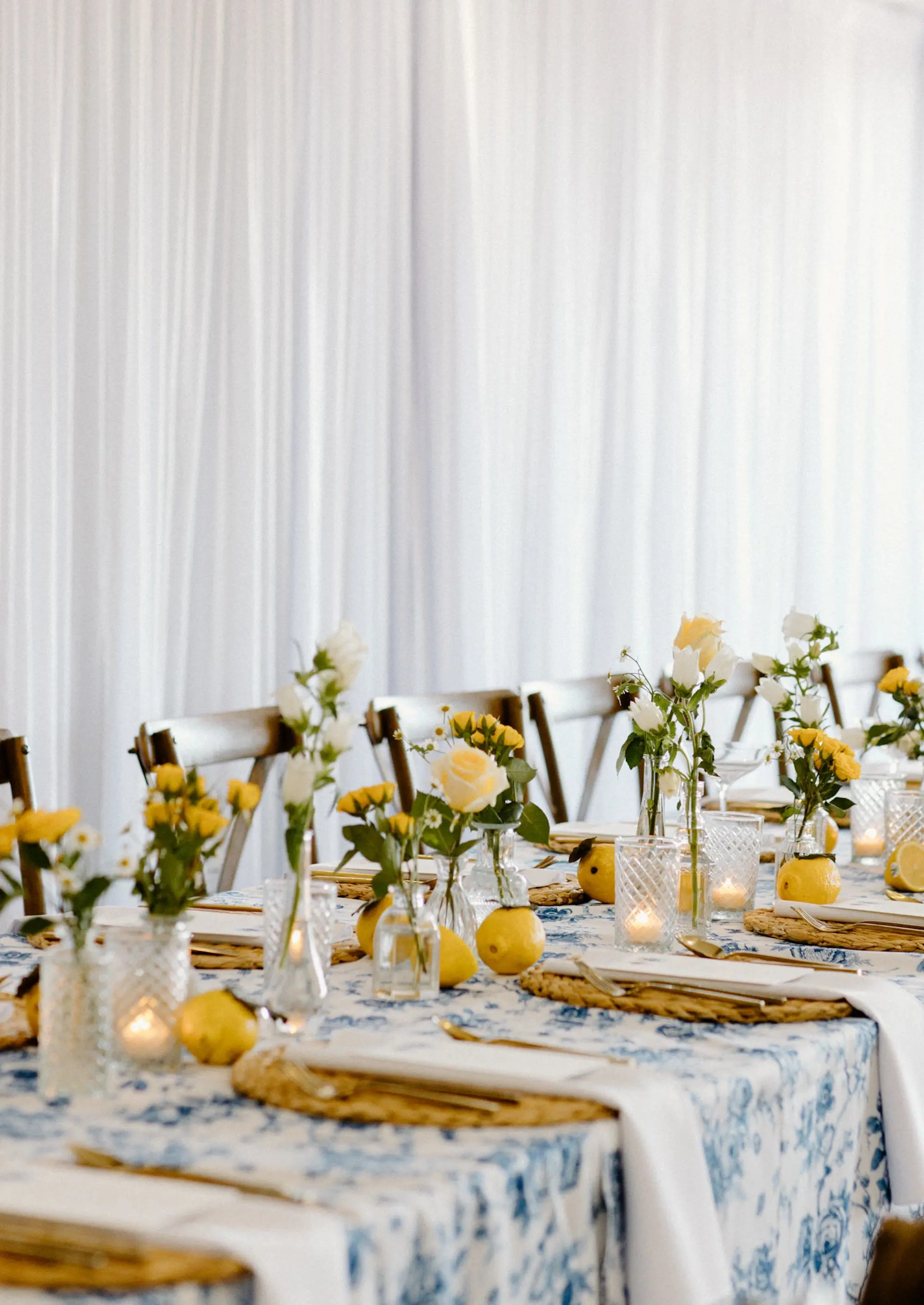 Blue and White Garden Rose Linen with Yellow and White Garden Theme Floral Centerpiece Wedding Reception Decor Inspiration | Lemon Citrus and Romantic Tea Candles with Wooden Chairs Reception Decor Ideas | Bud Vase with White and Yellow Rose Single Stem Centerpieces Inspiration | Tampa Bay Over The Top Linen Rentals | St Pete Rental A Chair Affair | Tampa Bay Planner Unique Weddings and Events
