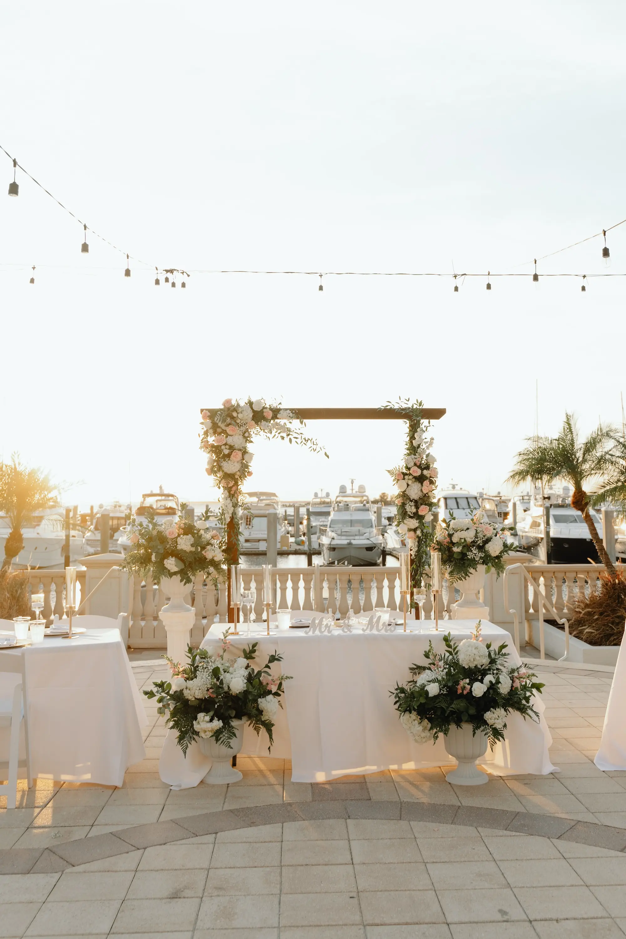 32Romantic Rose Gold and Champagne Wedding Ideas - “Best Of” 2025: Wedding Receptions Part 2 Outdoor Waterfront Wedding Reception Sweetheart Table Classic White Linens and Taper Candle Candle Table Decor Ideas | Wooden Altar Decor with White, Pink, and Greenery Flower Arrangement Decor Inspiration | Tampa Bay Florida Waterfront Wedding Venue Westshore Yacht Club
