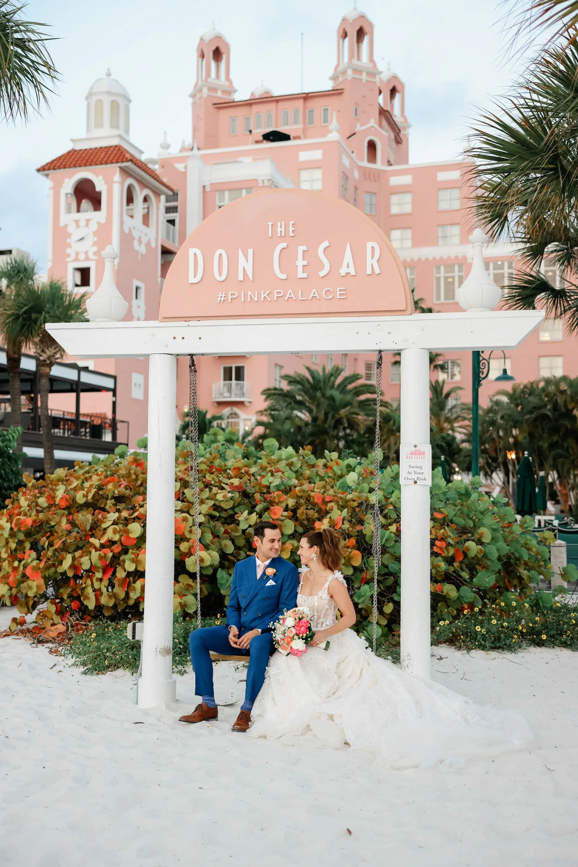 Bride and Groom Sitting on Beach Swing Chair Wedding Portrait | Beachfront Wedding Venue Historic St. Pete Beach Pink Hotel | St Pete Beach Wedding Venue Ideas The Don CeSar