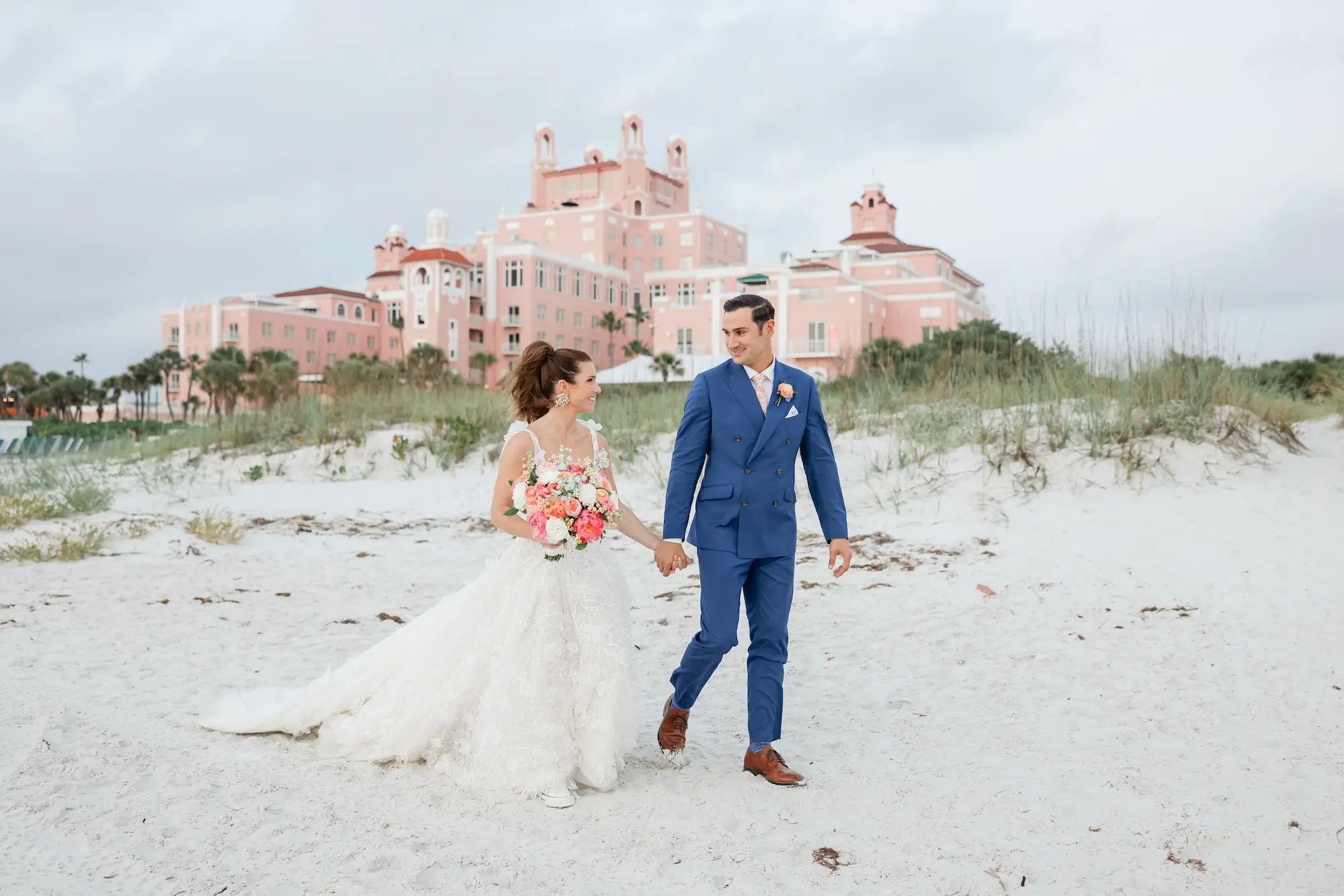 Bride and Groom Walking Down St Pete Beach Wedding Portrait | Lace and Tulle Galia Lahav Wedding Gown with Fitted Bodice and Full Layered, Ruffled Skirt and Train Ideas | White, Pink, Coral, Bridal Bouquet Inspiration | St Pete Photographer Lifelong Photography Studio | Historic St. Pete Beach Wedding Venue Don CeSar