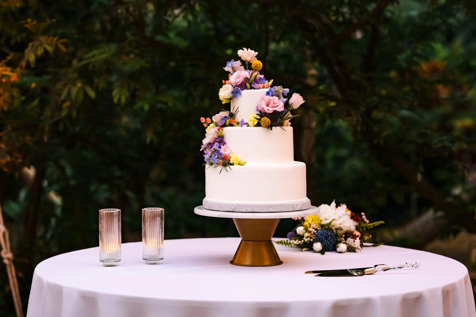 Three-Tiered Round White Wedding Cake with Pink, Purple, and Yellow Flower Accents
