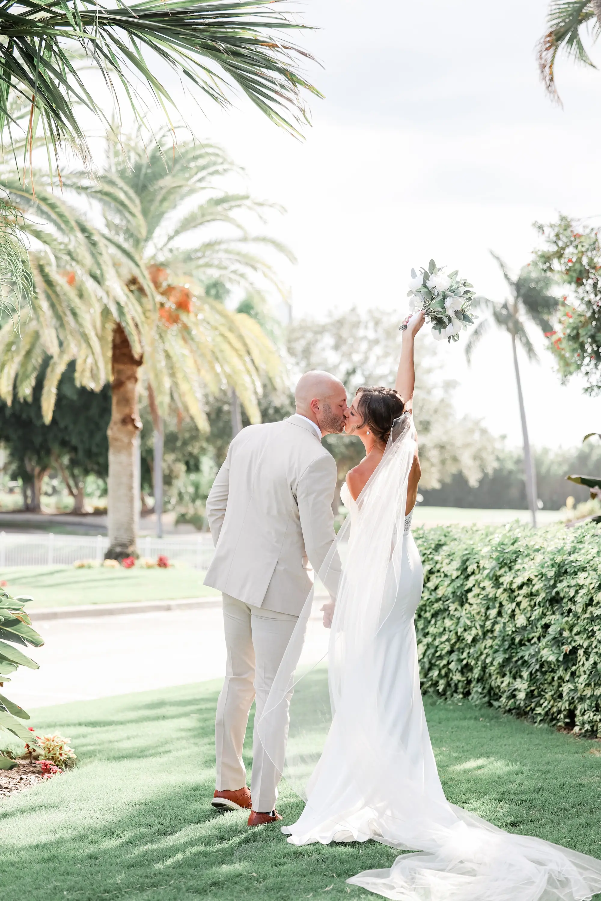 Bride and Groom Kissing Under Palm Tree Wedding Portrait | Traditional Long Veil Inspiration | Tan Groom Suit and Shoes Ideas | Outdoor Summer Florida Wedding Inspiration | St Pete Event Venue Isla Del Sol Yacht and Country Club | Tampa Bay Photographer Lifelong Photography Studio