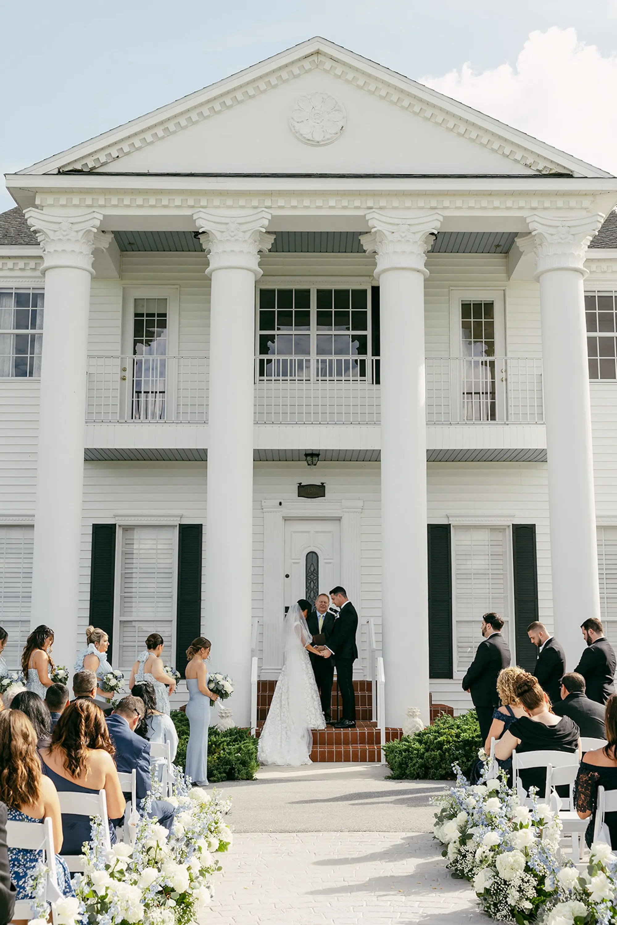 Bride and Groom Wedding Ceremony Vow Exchange Wedding | Southern Wedding Ceremony on Steps of Estate Inspiration | White Florals with Greenery and Light Blue Flower Arrangement Ceremony Aisle Decor Ideas | Tampa Bay Southern Estate Event Venue Legacy Lane Weddings