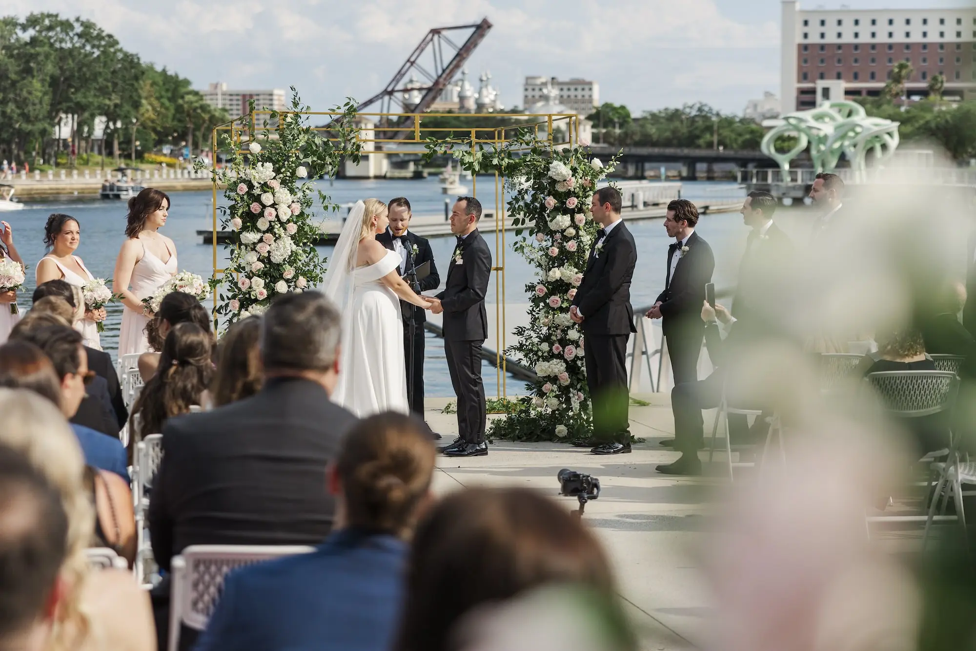Bride and Groom Outdoor Waterfront Wedding Ceremony Vow Exchange Wedding | Romantic Outdoor Riverfront Wedding Ceremony Inspiration | Gold Chuppah with Light Pink and White Cascading Florals and Greenery Ideas | Tampa Bay Florist Save The Date Florida | Florida Photographer Mary Anna Photography | Venue Tampa River Center
