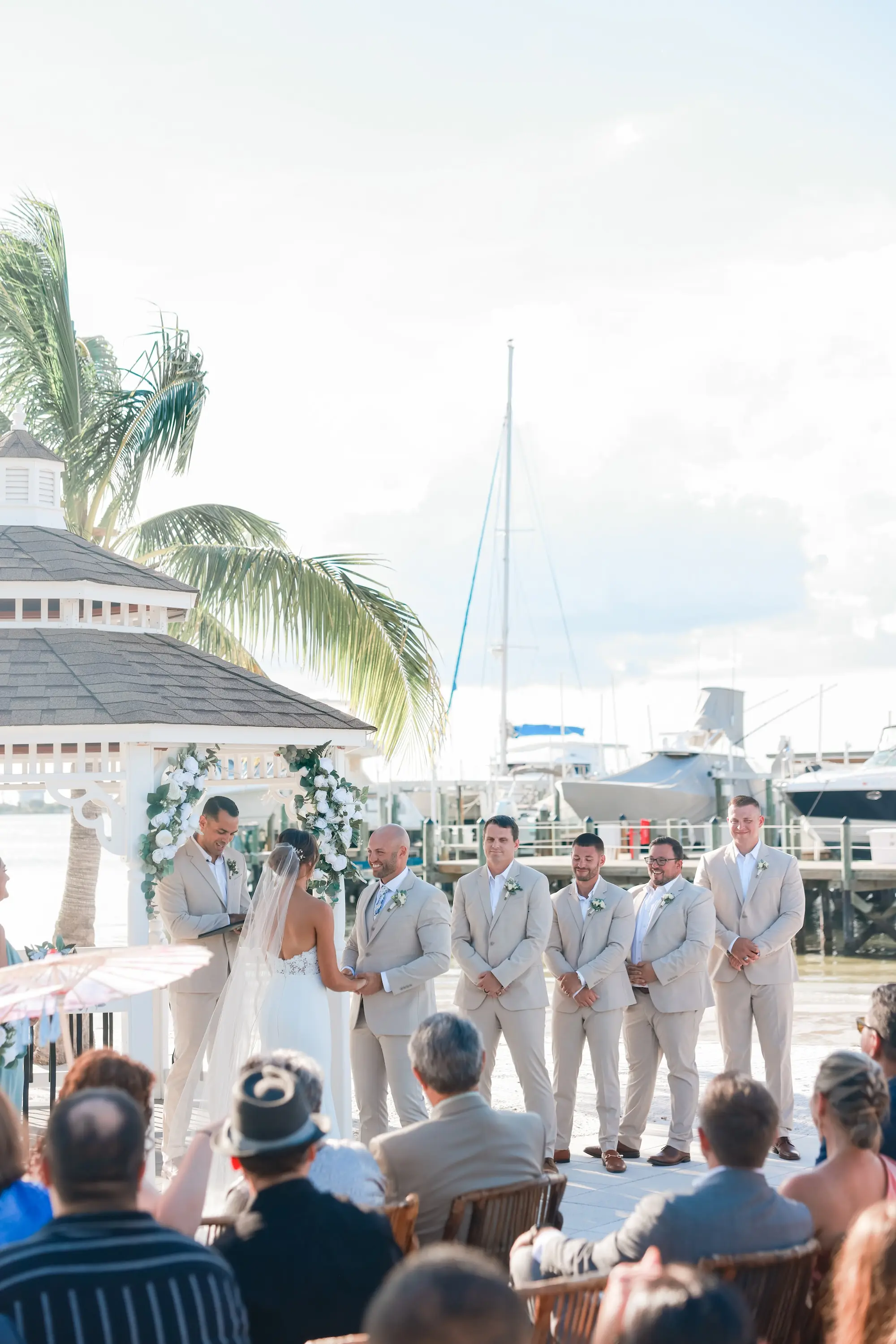 Bride and Groom Outdoor Waterfront Wedding Ceremony Vow Exchange Wedding Portrait | Classic White Roses and Greenery Floral Arrangements Gazebo Decor Ideas | Tan Groomsmen Suite Inspiration | St Pete Event Venue Isla Del Sol Yacht and Country Club | St Pete Photographer Lifelong Photography Studio