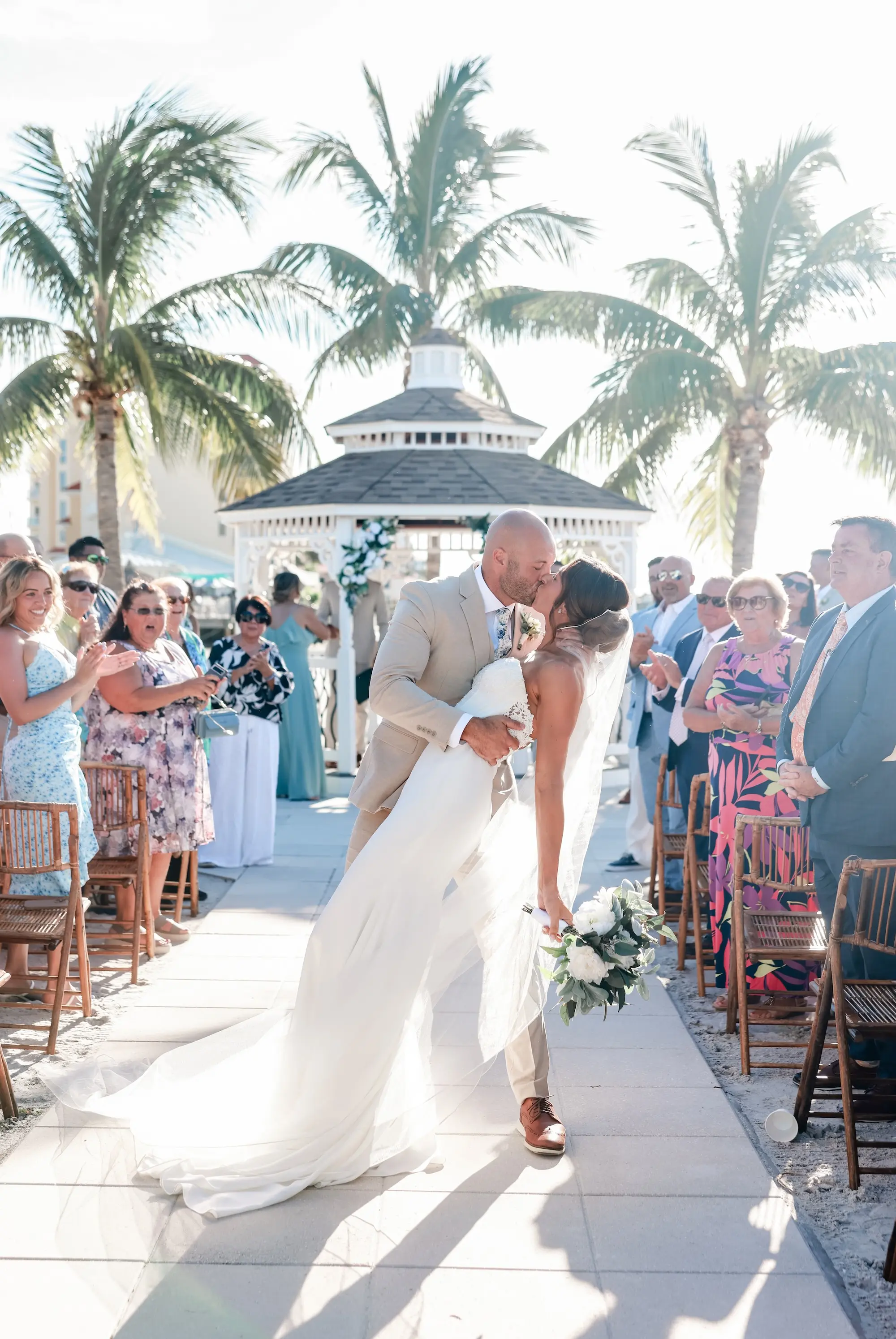 Bride and Groom Outdoor Waterfront Wedding Ceremony Kissing in Aisle Portrait | Classic White Roses and Greenery Floral Arrangements Gazebo Decor Ideas | Bamboo Wedding Ceremony Chairs Inspiration | St Pete Event Venue Isla Del Sol Yacht and Country Club | St Pete Photographer Lifelong Photography Studio
