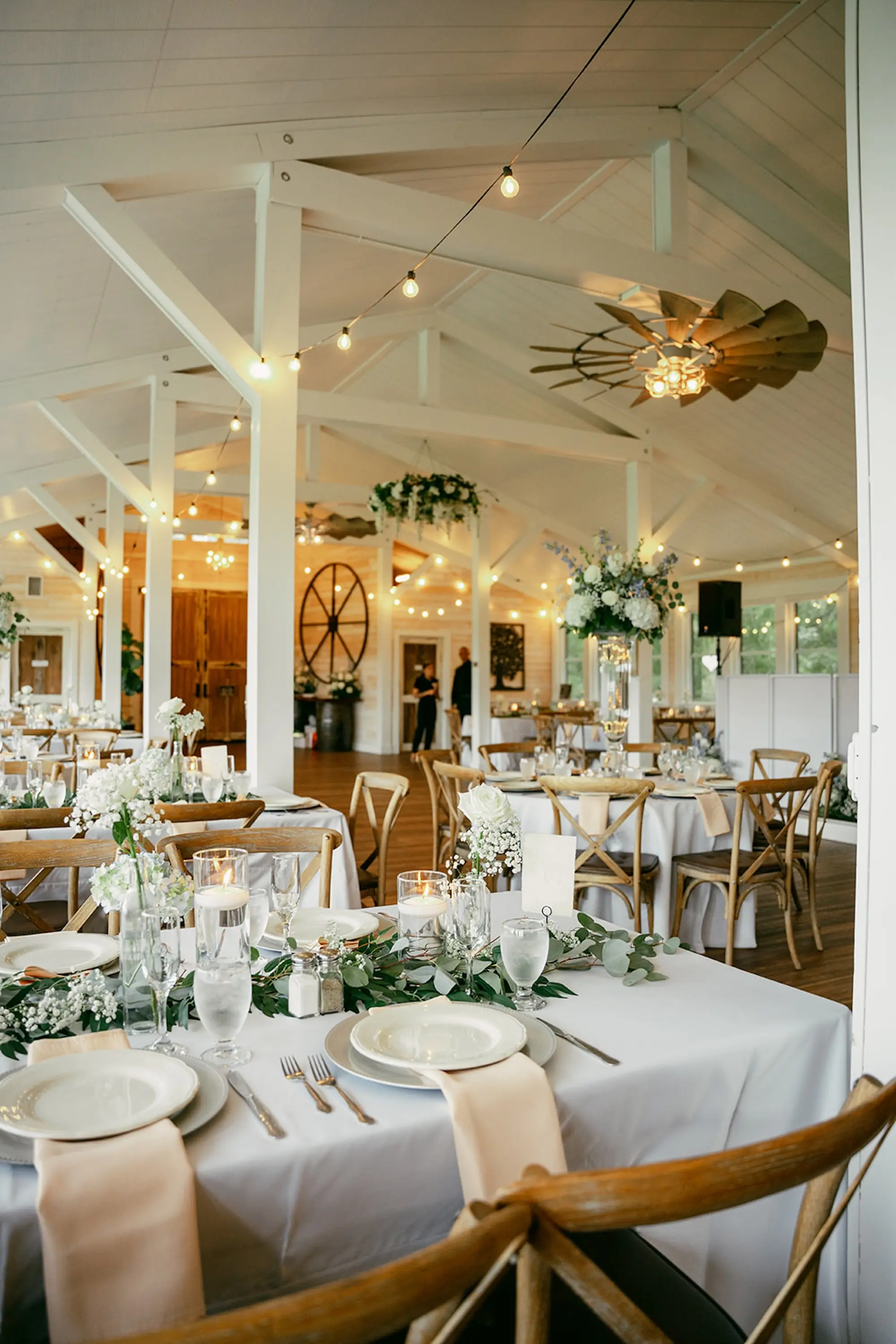 Elegant Rustic Barn Ballroom Wedding Reception | Garden Inspired White Hydrangeas, Baby's Breath, Roses with Blue Florals Centerpiece Decor Ideas Gold Chairs | Eucalyptus Garland Tabletop Decor Inspiration | White Table Linens with Wooden Chairs Wedding Reception Ideas | Tampa Bay Event Venue Legacy Lane Weddings