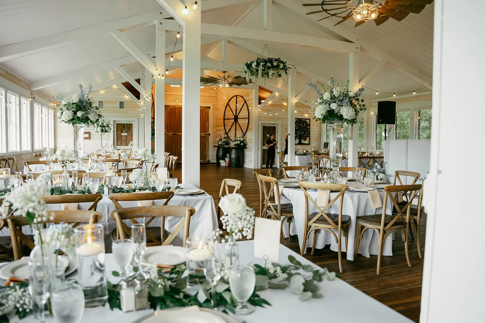 Elegant Rustic Barn Ballroom Wedding Reception | Garden Inspired White Hydrangeas, Baby's Breath, Roses with Blue Florals Centerpiece Decor Ideas Gold Chairs | Eucalyptus Garland Tabletop Decor Inspiration | White Table Linens with Wooden Chairs Wedding Reception Ideas | Tampa Bay Event Venue Legacy Lane Weddings