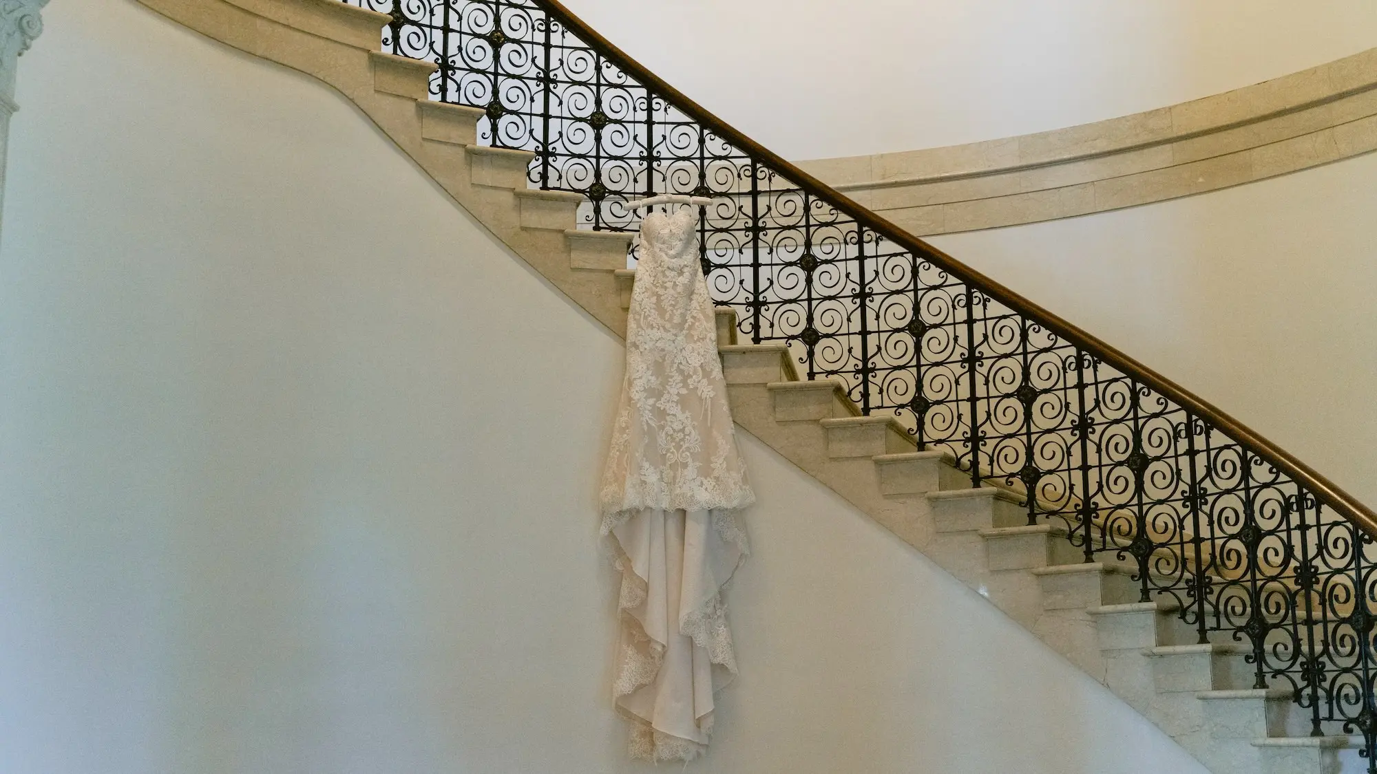 Lace Detailed Strapless Fit-and-Flare Mermaid Silhouette Maggie Sottero Wedding Gown with Sweetheart Neckline and Chapel-Length Train Hanging on Historic Staircase Rail Inspiration