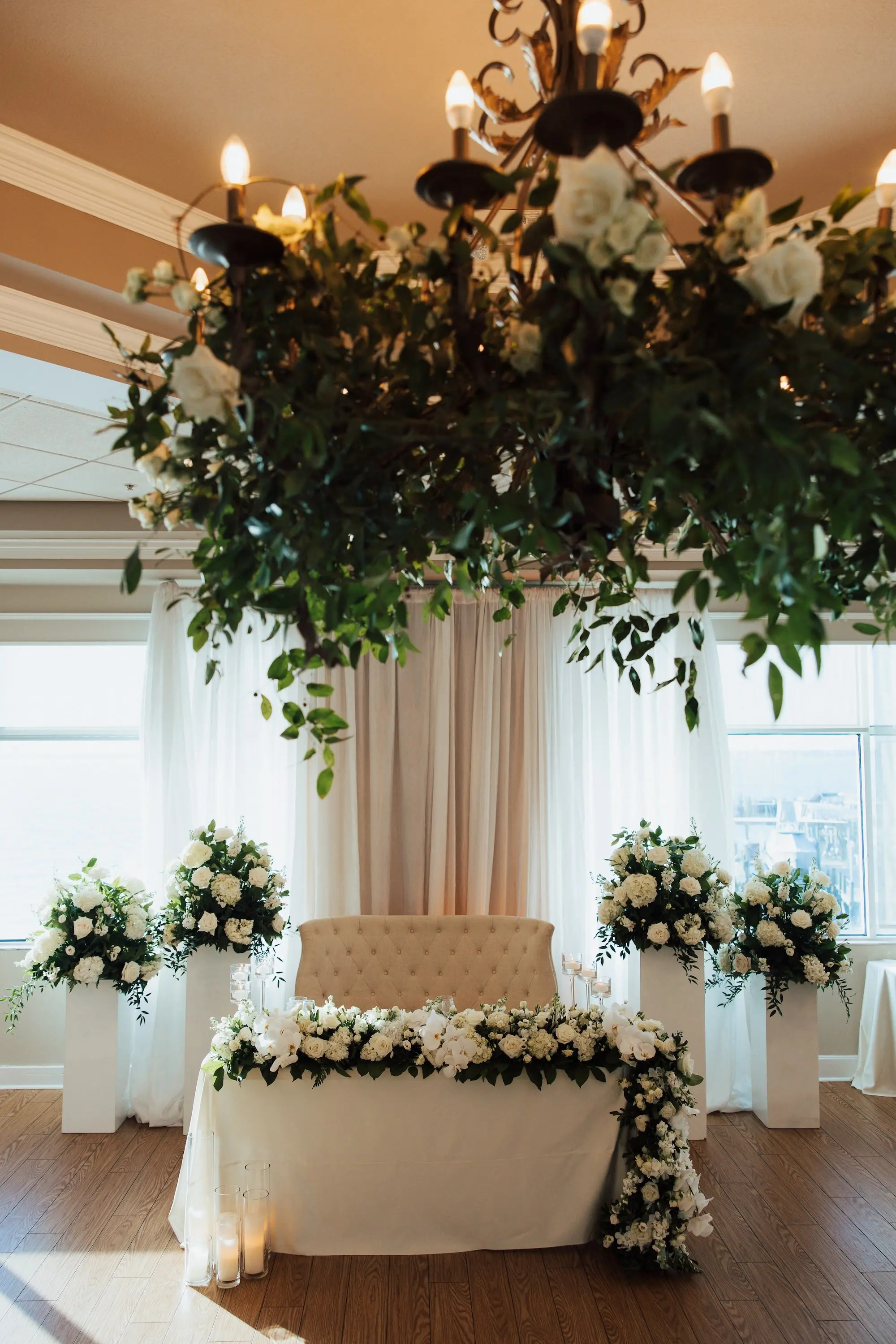 Luxurious Classic White Garden Theme Country Club Ballroom Wedding Reception | Eucalyptus Greenery with White Roses and Florals Wedding Reception Chandelier Decor Inspiration | Elegant Sweetheart Table with White Linens and White Floral Garland Decor Ideas | Tampa Bay Kate Ryan Event Rentals | Tampa Bay Event Venue Isla Del Sol Yacht and Country Club