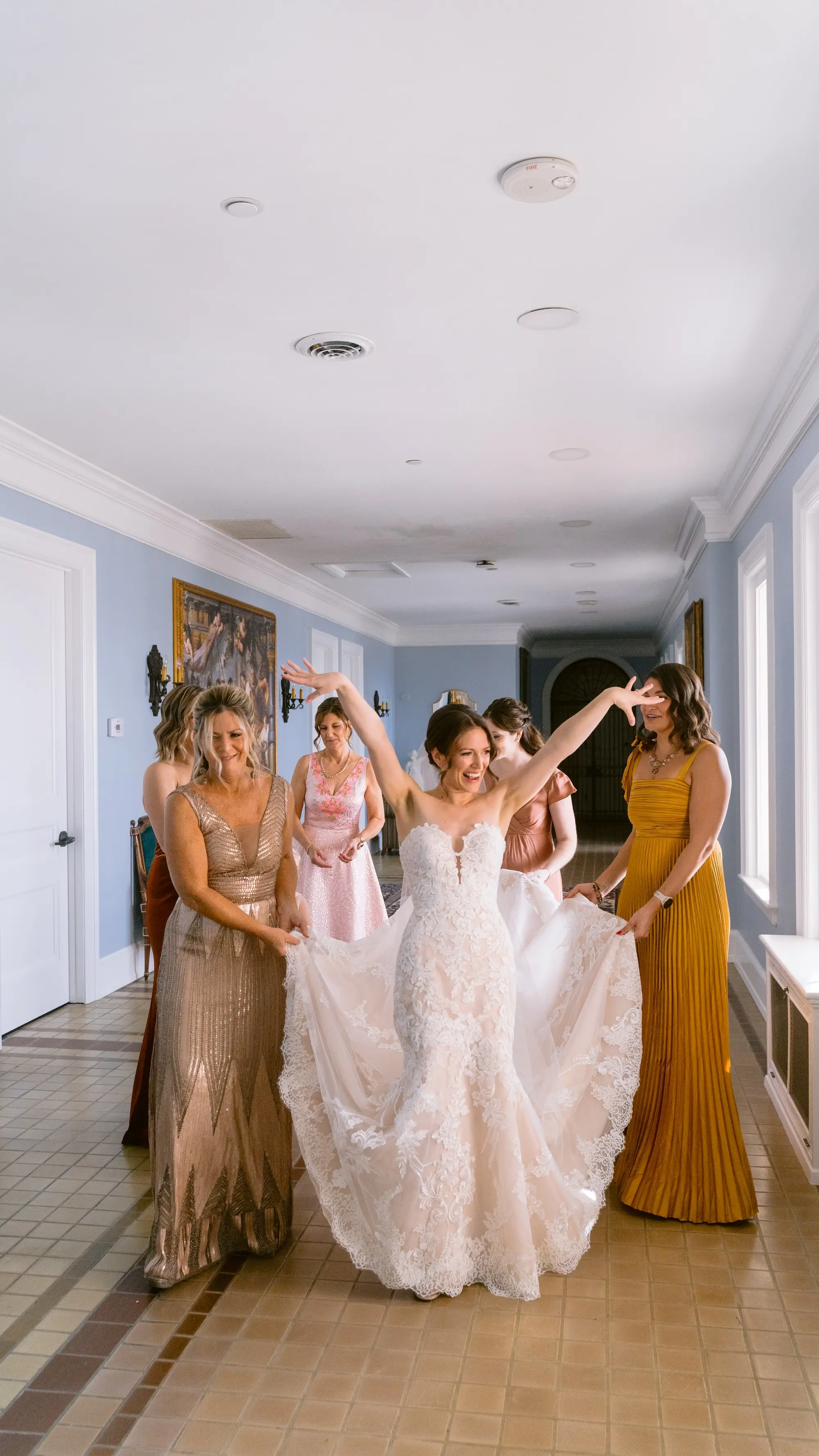 Bride and Bridesmaids Getting Ready Wedding Portrait | Different Shades of Orange and Yellow Bridesmaid Dress Inspiration | Lace Detailed Strapless Fit-and-Flare Mermaid Silhouette Maggie Sottero Wedding Gown with Sweetheart Neckline and Chapel-Length Train Ideas | Tampa Bay Photographer We The Blackwells