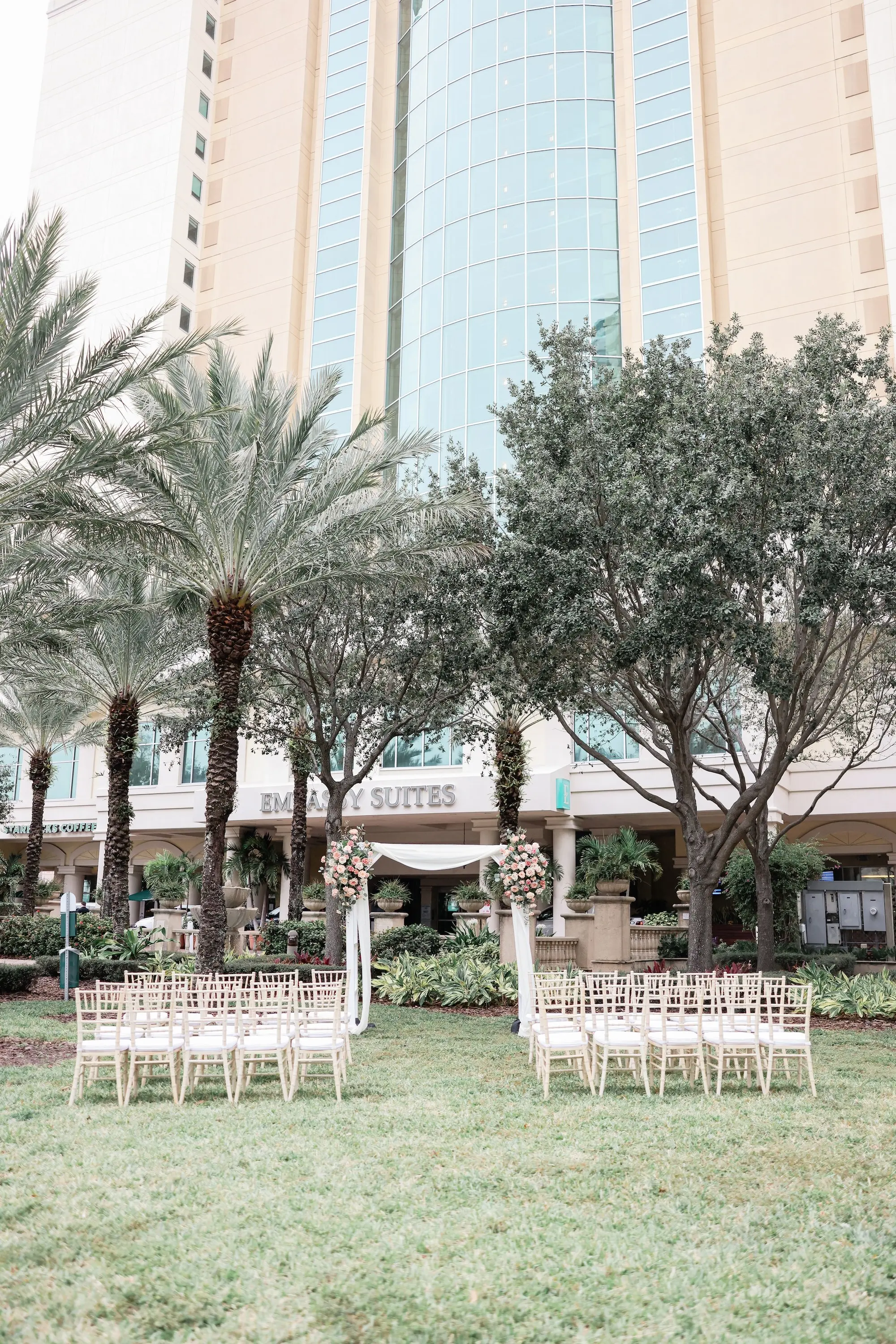 Outdoor Wedding Ceremony Venue Inspiration | Downtown Tampa Wedding Venue Ideas | Square Altar Arch with White Linen Draping and Florals Inspiration | Wedding Ceremony with White Bamboo Chairs Ideas | Venue Embassy Suites by Hilton Tampa Downtown Convention Center | Ceremony Decor Rentals A Chair Affair