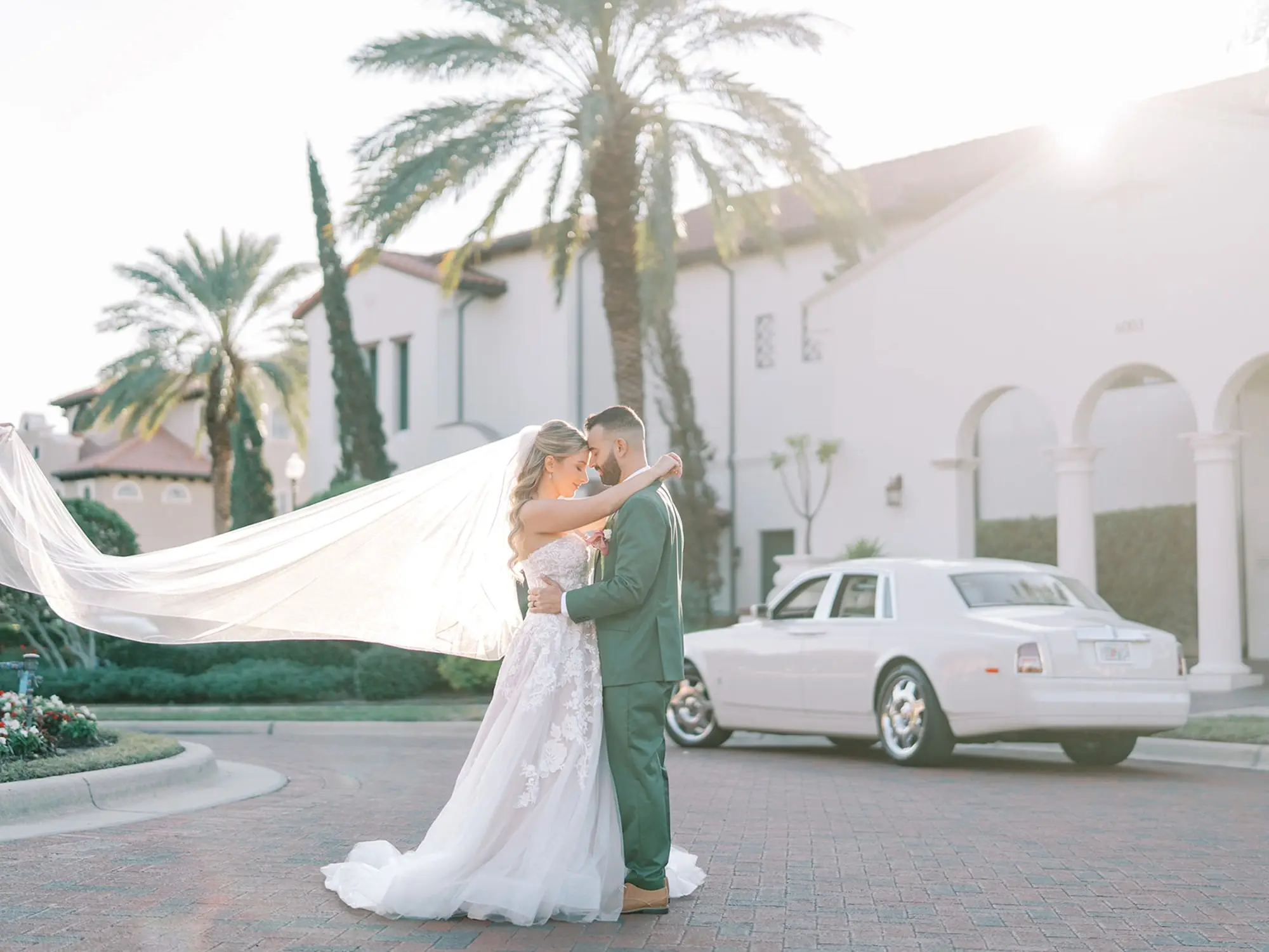 Bride and Groom with Flowing Veil Wedding Portrait | Soft Beach Curls Half Up Half Down Wedding Hair Ideas | Tampa Bay Wedding Hair and Makeup Artist Adore Bridal Hair and Makeup | Groom Green Three-Piece Suit Ideas | South Tampa Photographer Eddy Almaguer Photography | Traditional Longe Tulle Veil Inspiration | Waterfront South Tampa Venue Westshore Yacht Club