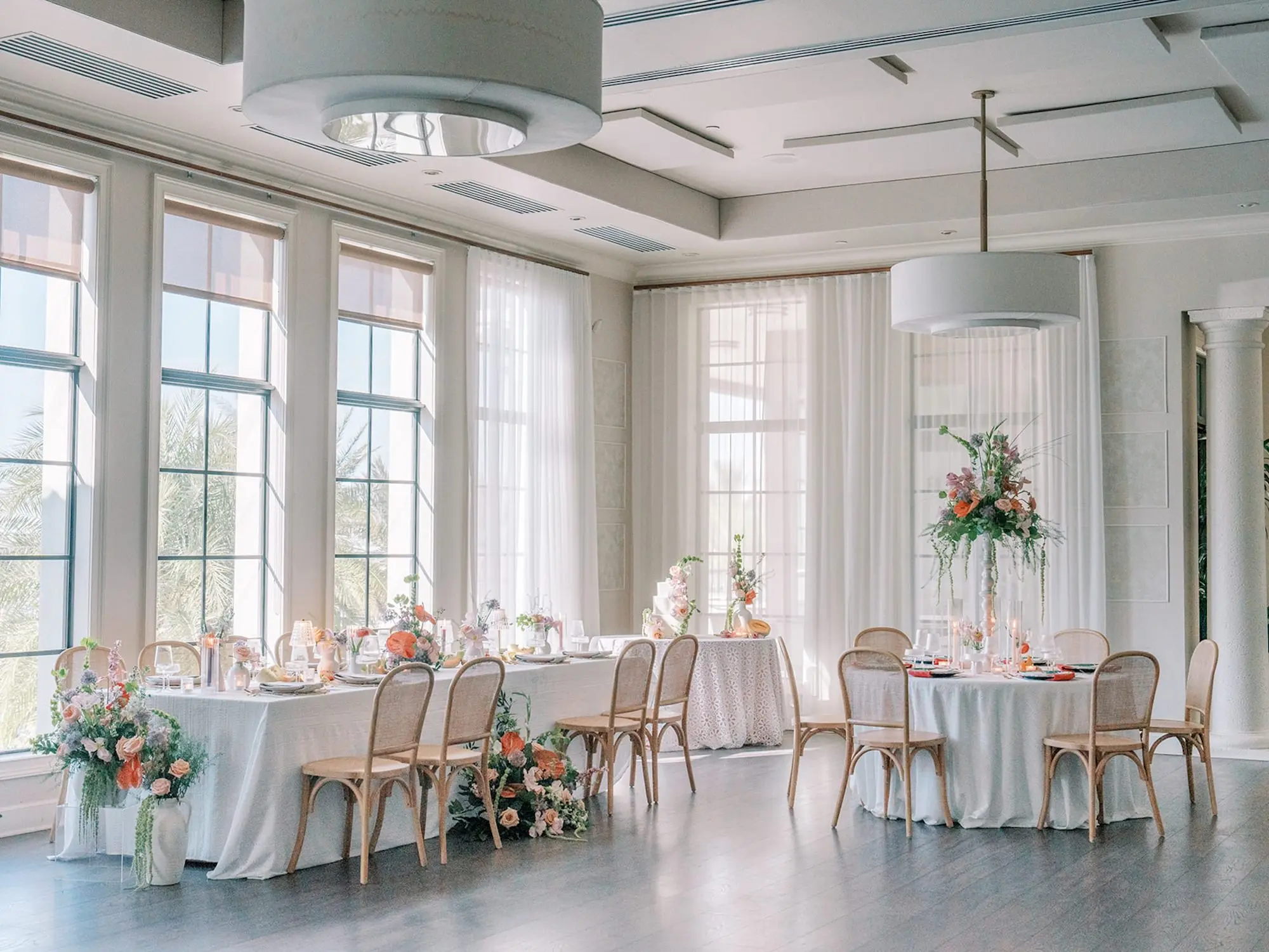 Luxurious Old Florida Ballroom Wedding Reception Portrait | Long and Round Wedding Reception Tables with Wicker Chairs with White Textured Linens with Bud Vases and Romantic Tea Candles Reception Decor Inspiration | Tropical Coral, Pink and White Orchids, Anthium, Ranunculus Reception Centerpiece Inspiration | Vibrant Fruit Dragon Fruit, Kiwi, Melon Table Decor Ideas | Tampa Bay Florist Save The Date Florida | Central Florida Event Planner MDP Events | Tampa Bay Over The Top Rental Linens | Wedding Venue Westshore Yacht Club