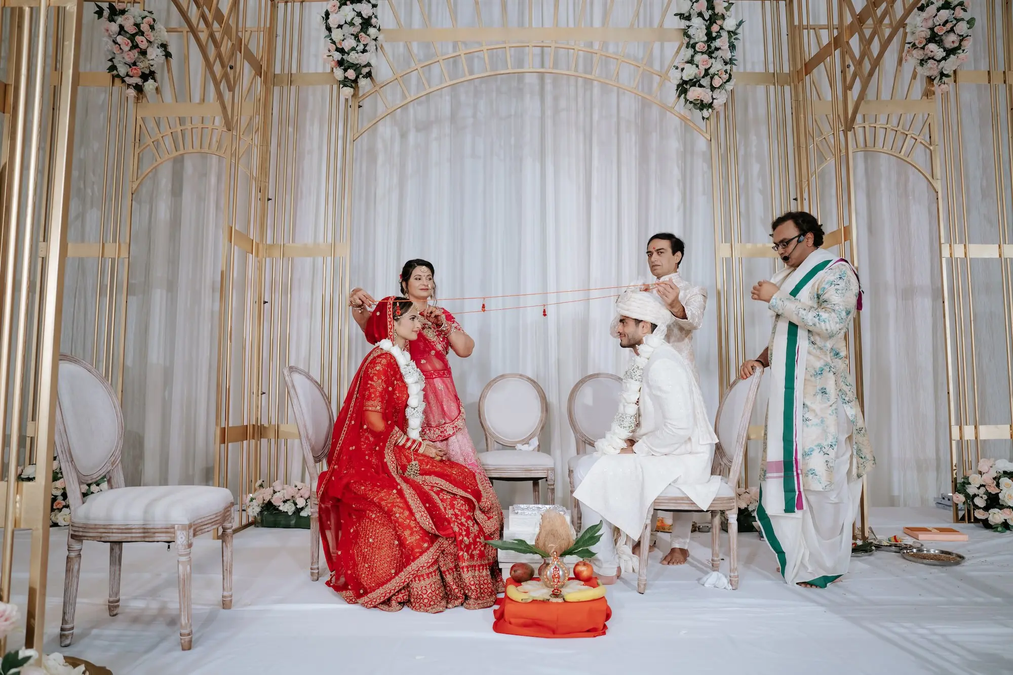 Traditional Red and Pink Indian Wedding Ceremony Decor Ideas | Gold Mandap with White and Blush Rose Flower Arrangement Inspiration | Bride Red Lehenga with Intricate Gold Embroidery Ideas | Red Matching Dupatta Ideas | Groom White Sherwani Turban and Stole Inspiration | Event Venue Grand Hyatt Tampa Bay