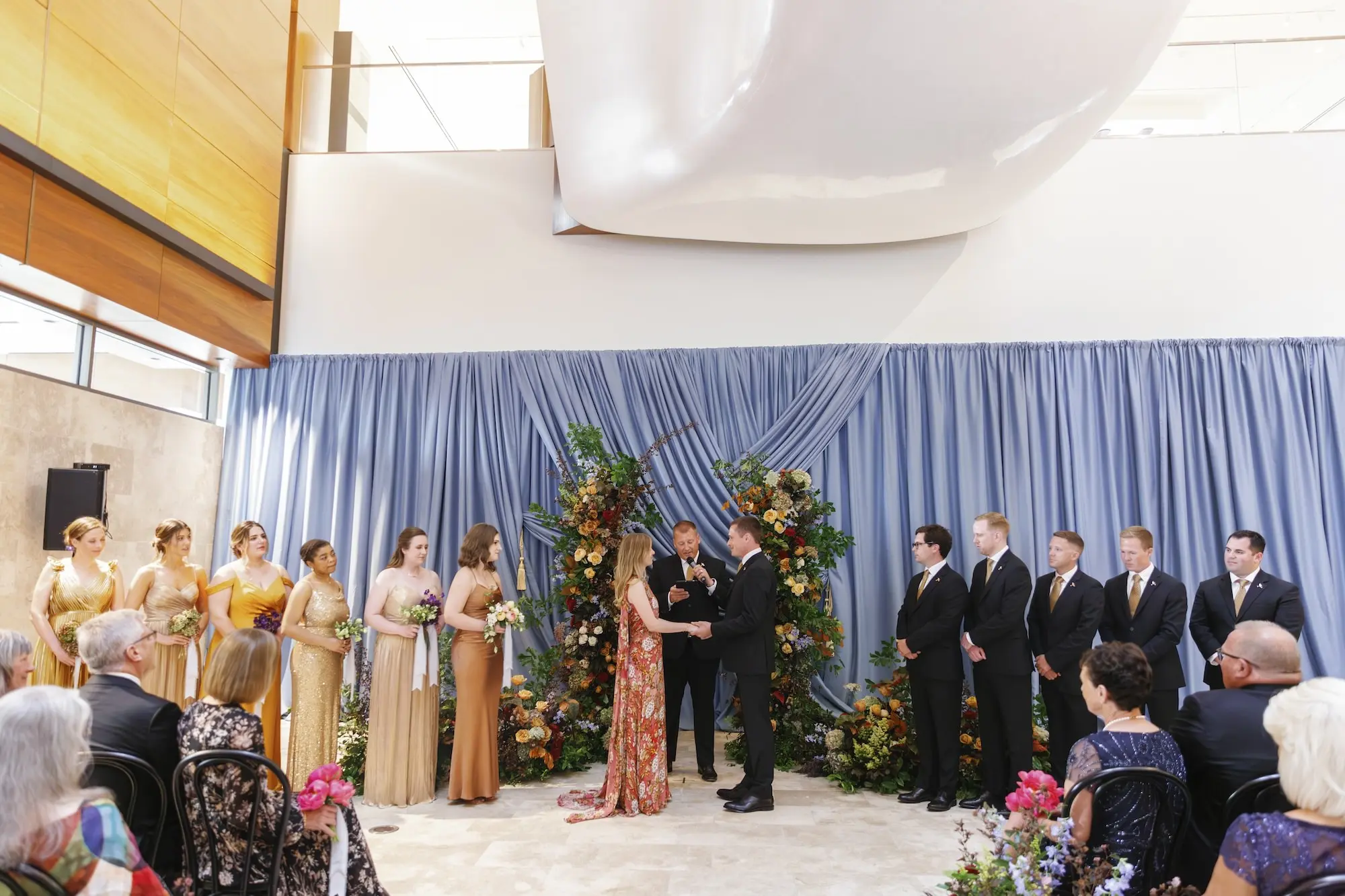 Bride and Groom Wedding Ceremony Vow Exchange Wedding | Different Colored Gold and Copper Bridesmaid Dresses Inspiration | Museum of the American Arts & Crafts Movement St Pete Wedding Venue | Rosy Pink Floral Mary Katrantzou Wedding Gown with Cape Inspiration | Traditional Black Wedding Ceremony Chairs and Dusty Blue and Orange Wall Draping Ideas | Floral Columns Ceremony Altar Decor Inspiration | Floral Arrangement Aisle Decor Ideas | St Pete Florist Bruce Wayne Florals | Florida Luxury Planner Parties A'La Carte