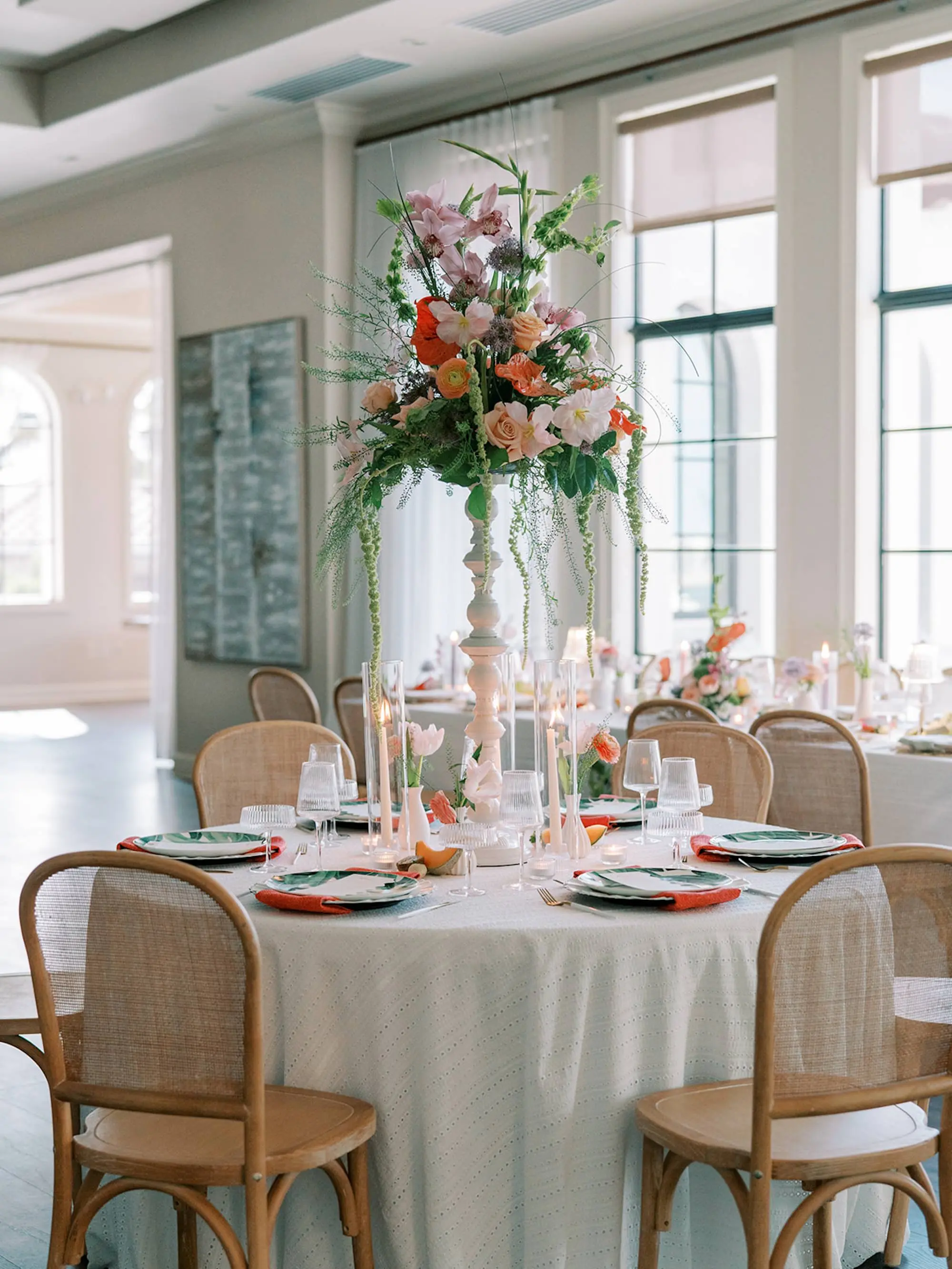 Luxurious Old Florida Ballroom Wedding Reception Portrait | Round Wedding Reception Tables with Wicker Chairs with White Textured Linens with Bud Vases and Romantic Tea Candles Reception Decor Inspiration | Tropical Coral, Pink and White Orchids, Anthium, Ranunculus Reception Centerpiece Inspiration | Vibrant Fruit Dragon Fruit, Kiwi, Melon Table Decor Ideas | Tampa Bay Florist Save The Date Florida | Central Florida Event Planner MDP Events | Tampa Bay Over The Top Rental Linens | Wedding Venue Westshore Yacht Club