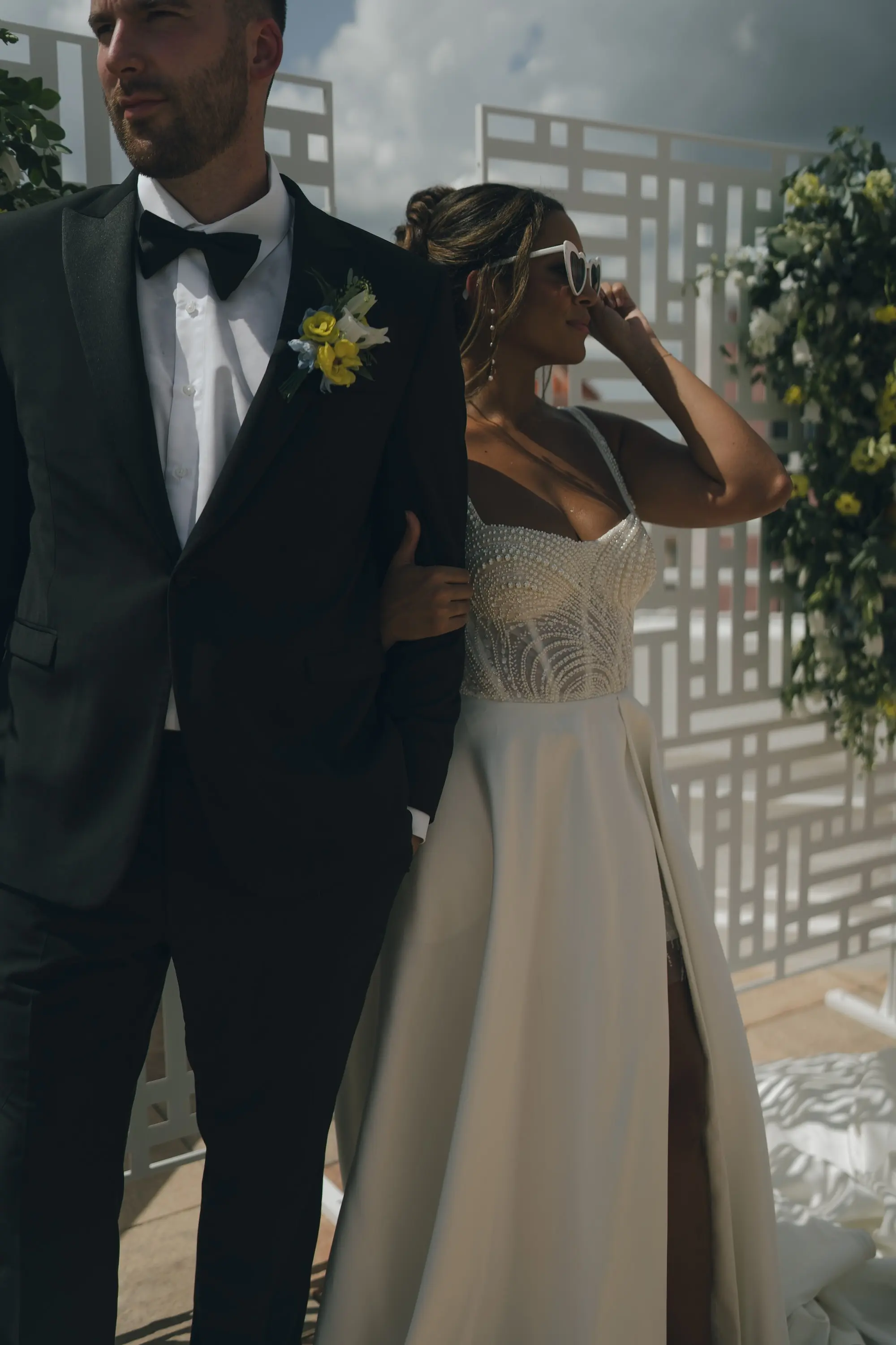 Bride and Groom Balcony Wedding Portrait | Outdoor Beachfront Wedding Ceremony Venue Inspiration | White and Yellow Roses and Florals in Lush Greenery Altar Ceremony Decor Ideas | Classic Groom Black and White Tuxedo Inspiration | Satin Ballgown with Corset Top and Slit Wedding Dress Boutique Truly Forever Bridal Tampa | Updo with Loose Beach Curls Wedding Hair Inspiration | Romantic Bridal Wedding Hair Updo and Makeup Ideas | Hair and Makeup Artist Lasting Luxe | Photographer Amber Yonker Photography | St Pete Beach Wedding Venue Don CeSar