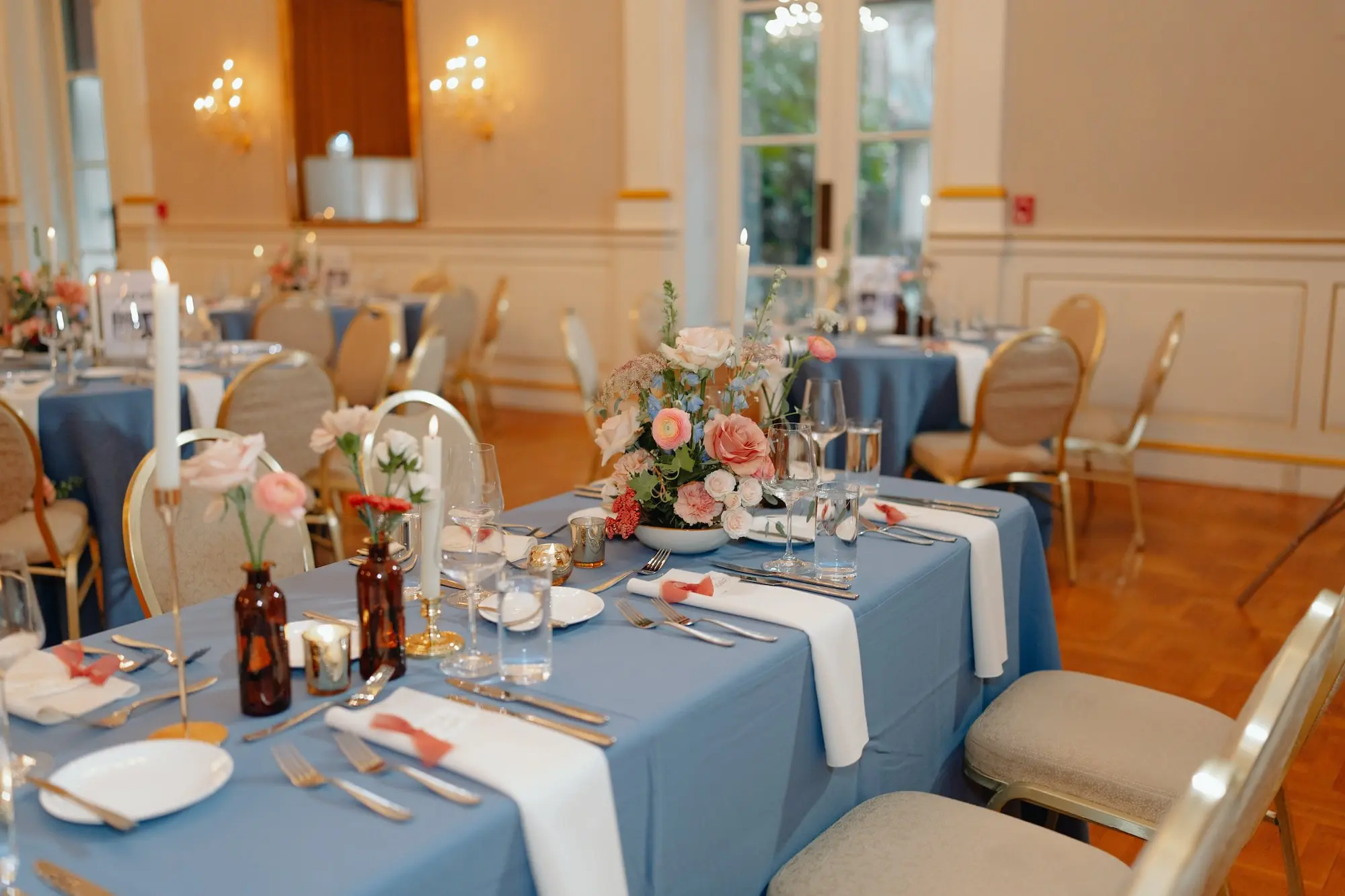 Soft Romantic Ballroom Wedding Reception | Modern Gold King Louis XIV Chairs | Classic Dusty Blue Linen Tablecloths with Sophisticated Taper Candles Tablescape Decor Inspiration | White Linen Napkins with Colored Bud Vases and Single Stem Orange, Pink, Mauve, Champagne Floral Centerpiece Ideas | Tampa Bay Planner Wilder Mind Events