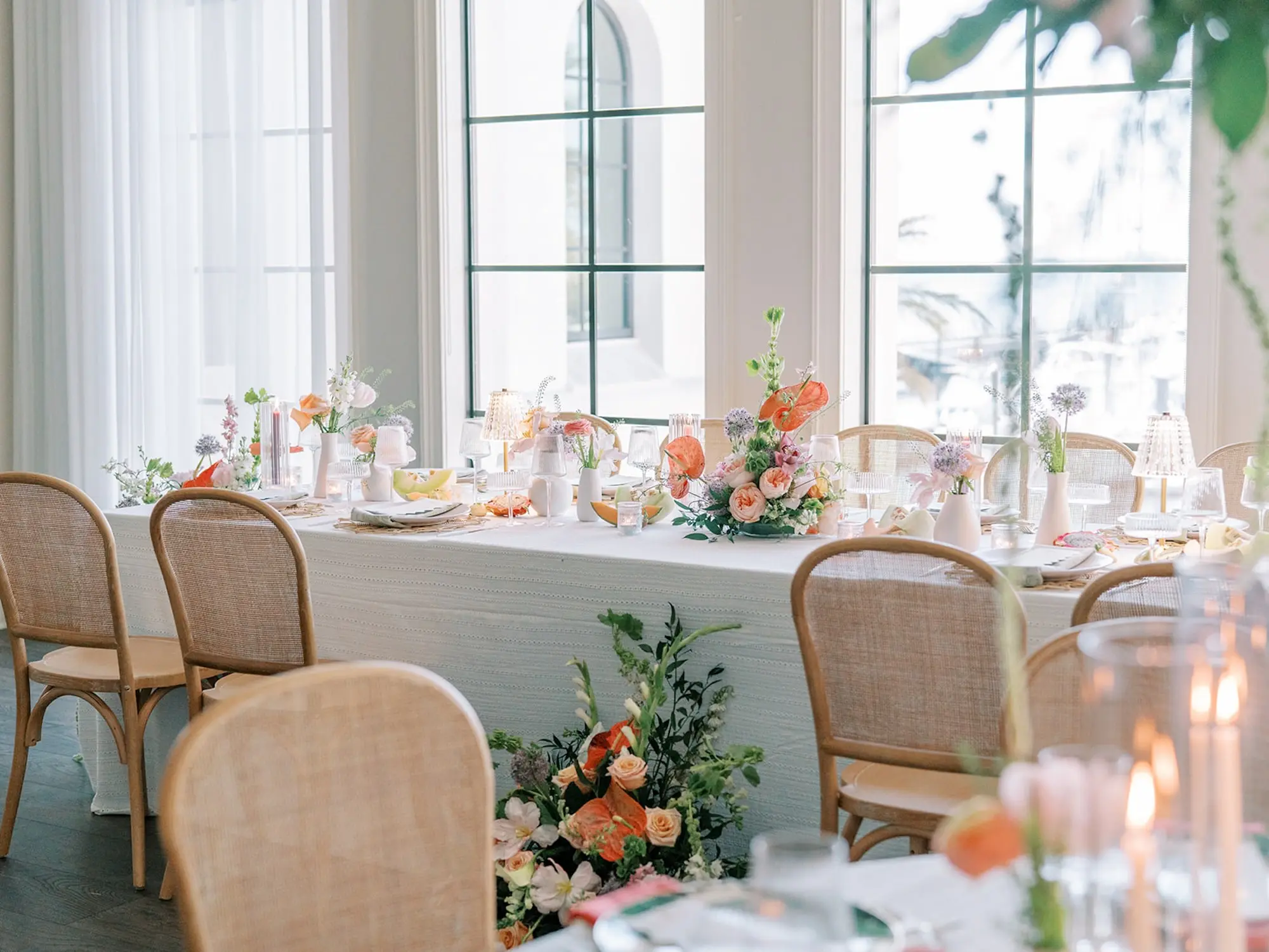 Luxurious Old Florida Ballroom Wedding Reception Portrait | Long Wedding Reception Tables with Wicker Chairs with White Textured Linens with Bud Vases and Romantic Tea Candles Reception Decor Inspiration | Tropical Coral, Pink and White Orchids, Anthium, Ranunculus Reception Centerpiece Inspiration | Vibrant Fruit Dragon Fruit, Kiwi, Melon Table Decor Ideas | Tampa Bay Florist Save The Date Florida | Central Florida Event Planner MDP Events | Tampa Bay Over The Top Rental Linens | Wedding Venue Westshore Yacht Club