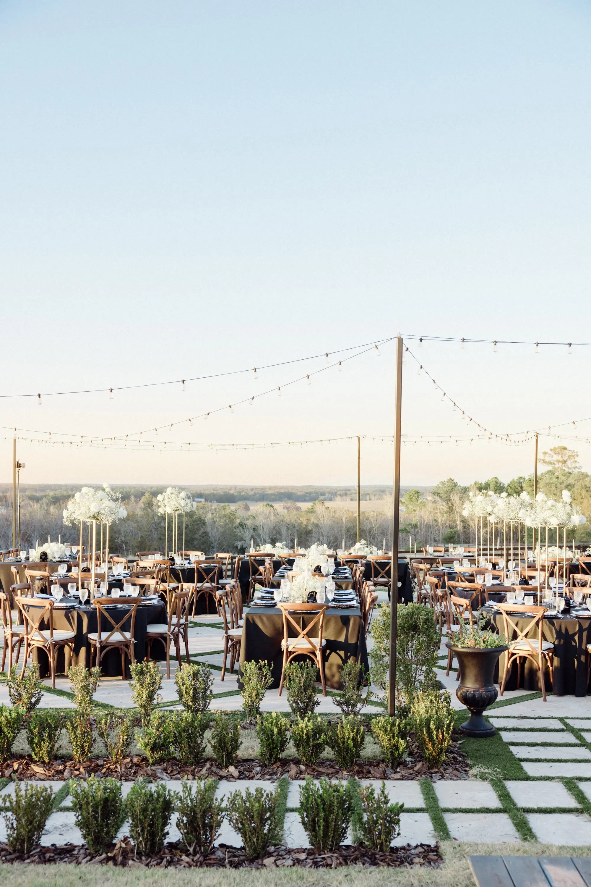 Outdoor European Inspired Black and White Winter Wedding with Travertine Terrace Reception Inspiration | Outside String Lights Reception Decor Ideas | Tall Monochromatic White Centerpieces on Gold Vases Inspiration | Wooden Chairs Decor Ideas | Brooksville Event Venue La Hacienda on Snow Hill