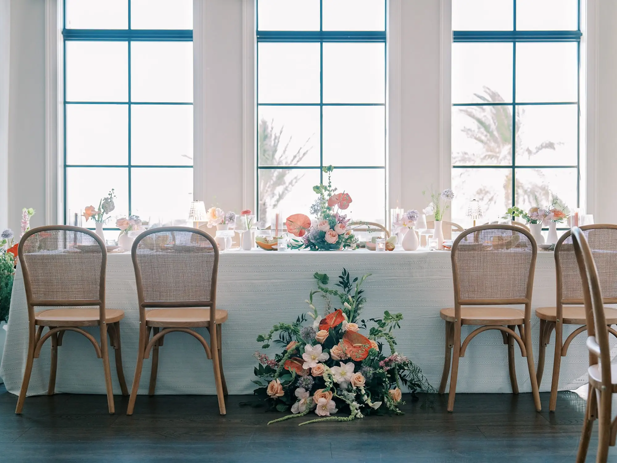 Luxurious Old Florida Ballroom Wedding Reception Portrait | Long Wedding Reception Table with Wicker Chairs with White Textured Linens with Bud Vases and Romantic Tea Candles Reception Decor Inspiration | Tropical Coral, Pink and White Orchids, Anthium, Ranunculus Reception Centerpiece Inspiration | Vibrant Fruit Dragon Fruit, Kiwi, Melon Table Decor Ideas | Tampa Bay Florist Save The Date Florida | Central Florida Event Planner MDP Events | Tampa Bay Over The Top Rental Linens | Wedding Venue Westshore Yacht Club