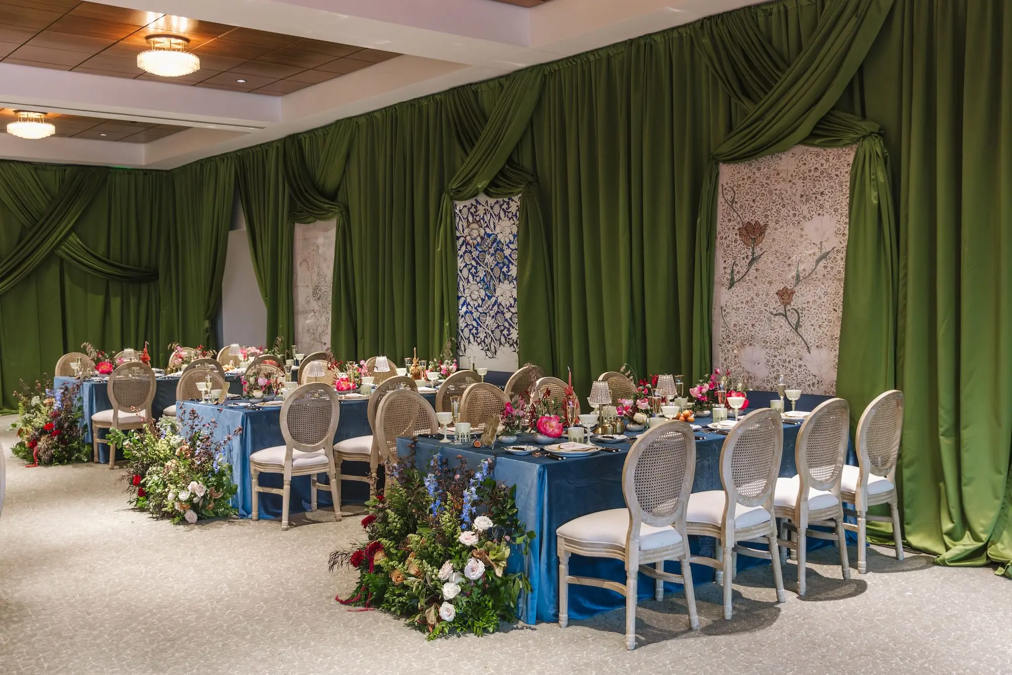 Luxurious Wedding Reception with Long Tables with Azure Blue Linens and King Louis Gold and Wicker Chairs and Green Linen Wall Drapings | Taper Candle Centerpieces and Floral Arrangements with Vibrant Colorful Florals in Red, Blue, Green, Violey, and Blush Arrangement Ideas | St Pete Florist Bruce Wayne Florals | Florida Luxury Planner Parties A'La Carte | Museum of the American Arts & Crafts Movement St Pete Wedding Venue
