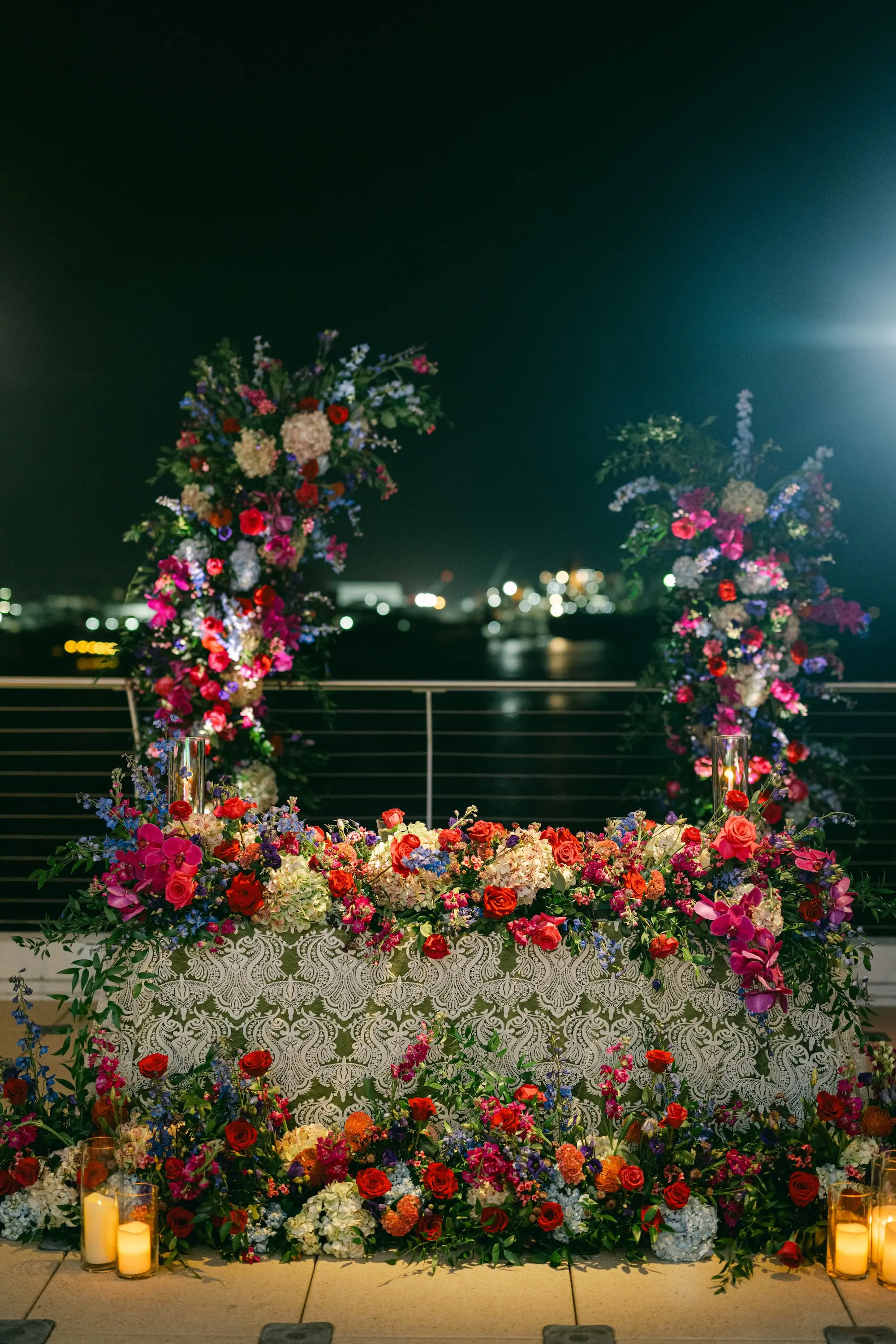 Romantic Jewel-Toned Sweetheart Table with Asymmetrical Floral Columns of Pink, Red, Purple, and Blue Flowers Roses, Hydrangeas, Wisteria Arrangements and Greenery Wedding Reception Decor Ideas | Tampa Bay Planner Blue Skies Weddings and Events