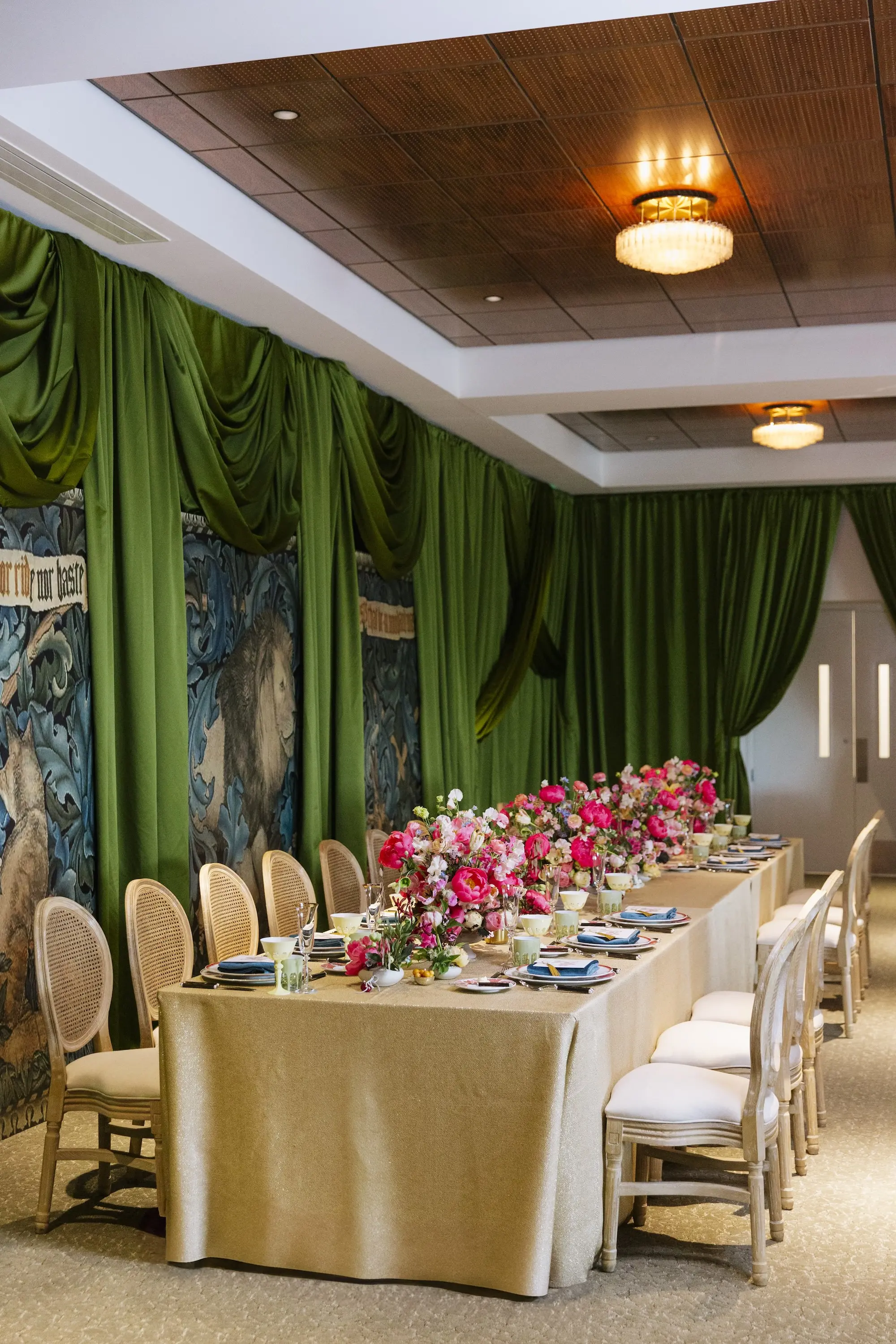 Luxurious Wedding Reception | Long Table with Gold Linen and King Louis Gold and Wicker Chairs and Green Linen Wall Drapings | Lush Floral Centerpieces with Vibrant Colorful Florals in Red, Blue, Green, Violey, and Blush Arrangement Ideas | St Pete Florist Bruce Wayne Florals | Florida Luxury Planner Parties A'La Carte | Museum of the American Arts & Crafts Movement St Pete Wedding Venue