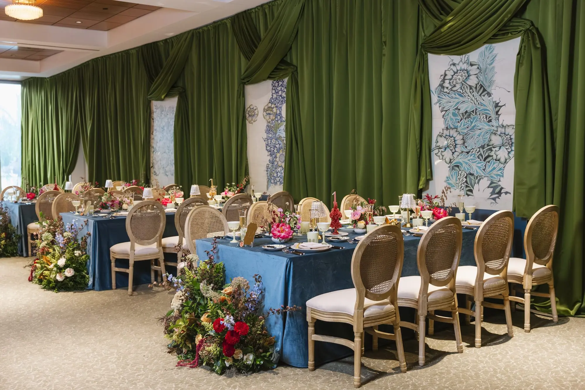 Luxurious Wedding Reception with Long Tables with Azure Blue Linens and King Louis Gold and Wicker Chairs and Green Linen Wall Drapings | Taper Candle Centerpieces and Floral Arrangements with Vibrant Colorful Florals in Red, Blue, Green, Violey, and Blush Arrangement Ideas | St Pete Florist Bruce Wayne Florals | Florida Luxury Planner Parties A'La Carte | Museum of the American Arts & Crafts Movement St Pete Wedding Venue