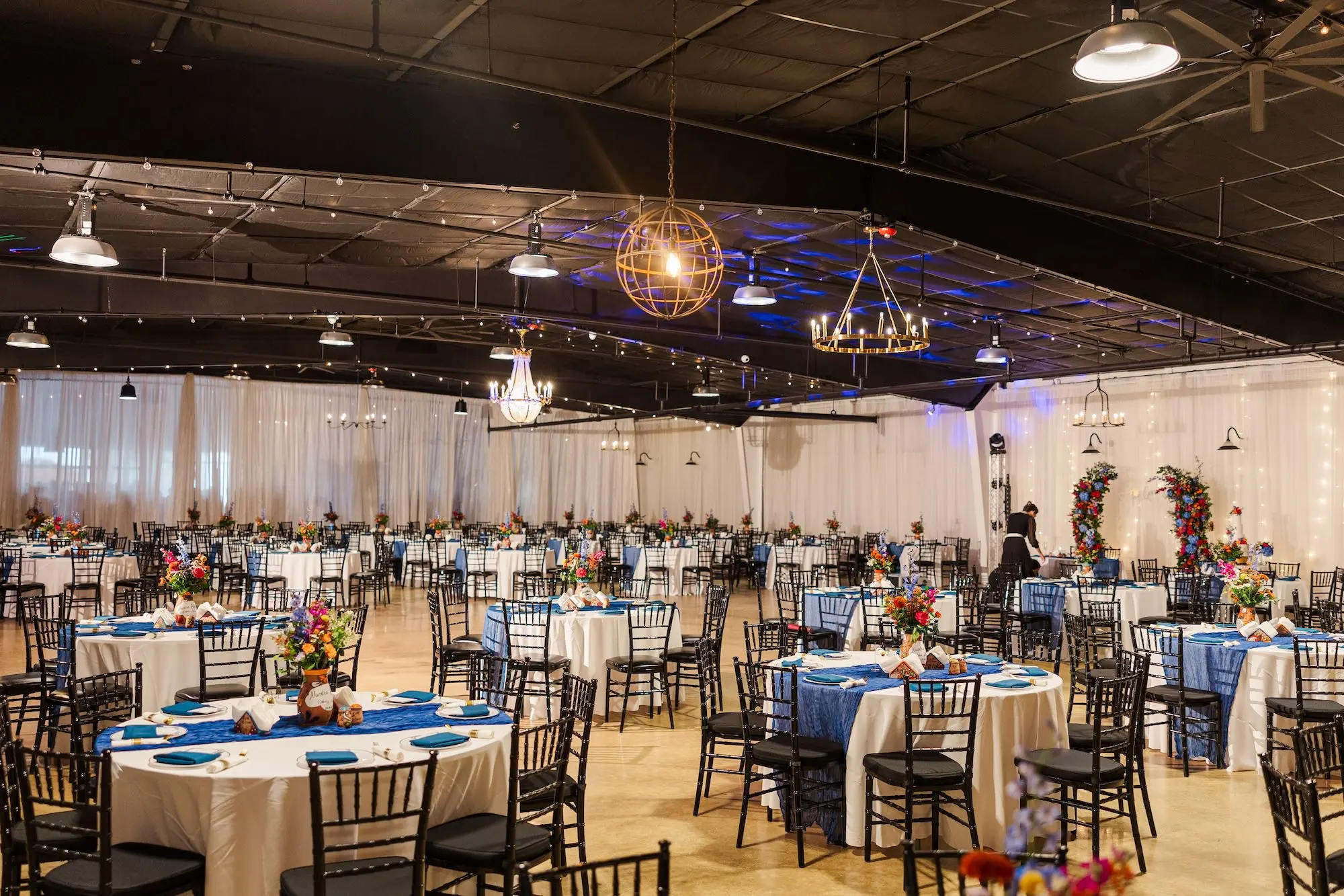 27Vibrant Blue Mexican Wedding Ideas Central Florida Venue 650 - Blue Mexican-Inspired Winter Haven Wedding | Venue 650 Rustic Industrial Ballroom Wedding Reception | Black Chiavari Chairs | Mexican Pottery Vases Centerpieces with Vibrant Red, Blue, Yellow, Green Floral Arrangement Ideas | Tables and Chairs Rentals A Chair Affair | White Haven Wedding Venue Venue 650