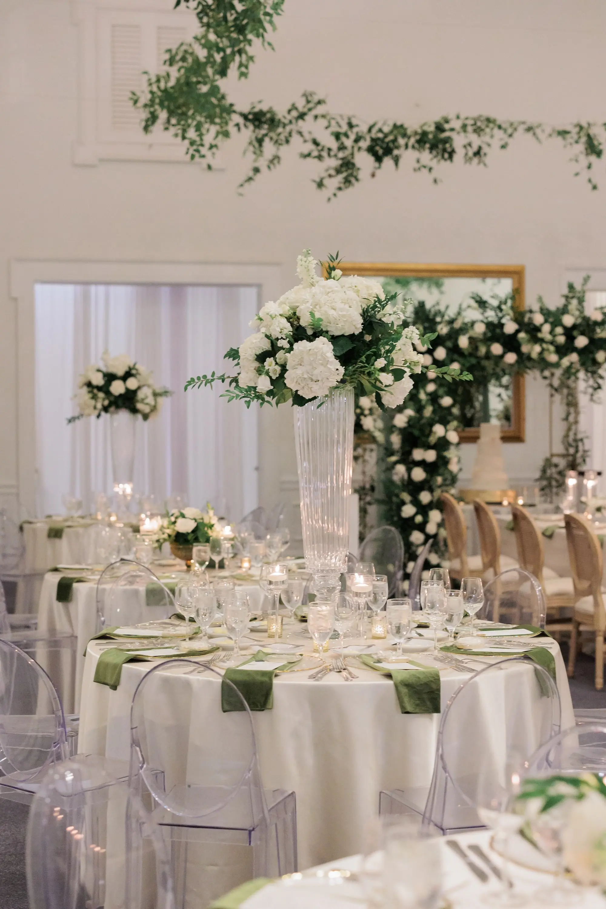 Timeless Ballroom Wedding Reception | Modern Clear Ghost Chairs | Tall Glass Centerpieces with White Hydrangeas, Roses, and Orchid Flower Arrangement Ideas | Greenery Eucalyptus Garland Decor Inspiration | White Linens with Olive Green Napkins and Romantic Candlelight Tablescape Decor Ideas | Tampa Bay Kate Ryan Event Rentals | Florist Save The Date Florida | Planner EventFull Weddings
