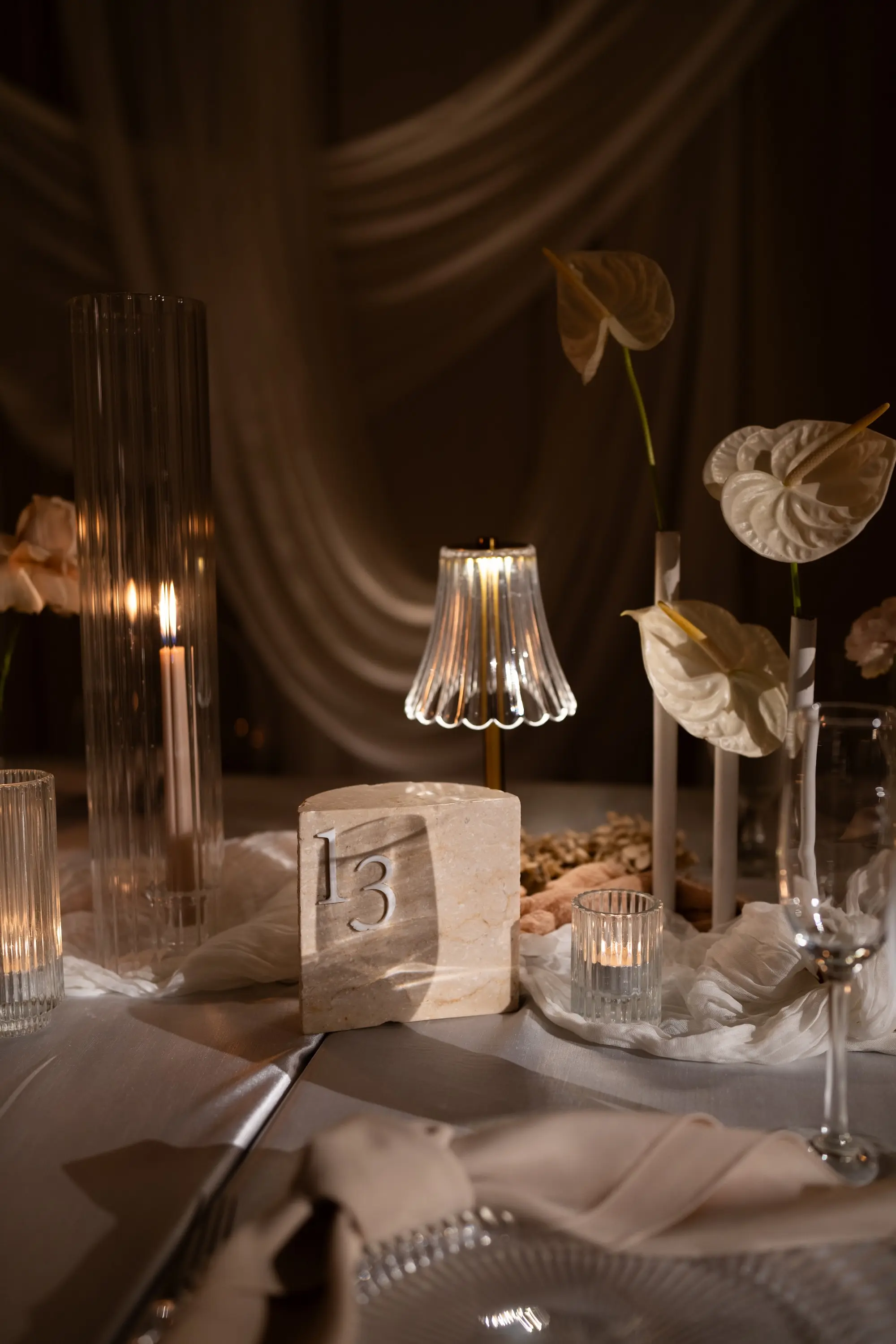 Soft, Romantic Ballroom Wedding Reception Tablescape Inspiration | Ethereal Candlelight Decor Ideas | Single Stem Anthuriums and Roses Florals in Glass Bud Vase Wedding Reception Table Decor Inspiration | White, Cream, and Soft Gold Wedding Reception Decor Ideas | White Linens with Candles and Small Decorative Table Lamps Inspiration | Stone Quartz Table Number Ideas | Tampa Bay Planner EventFull Weddings