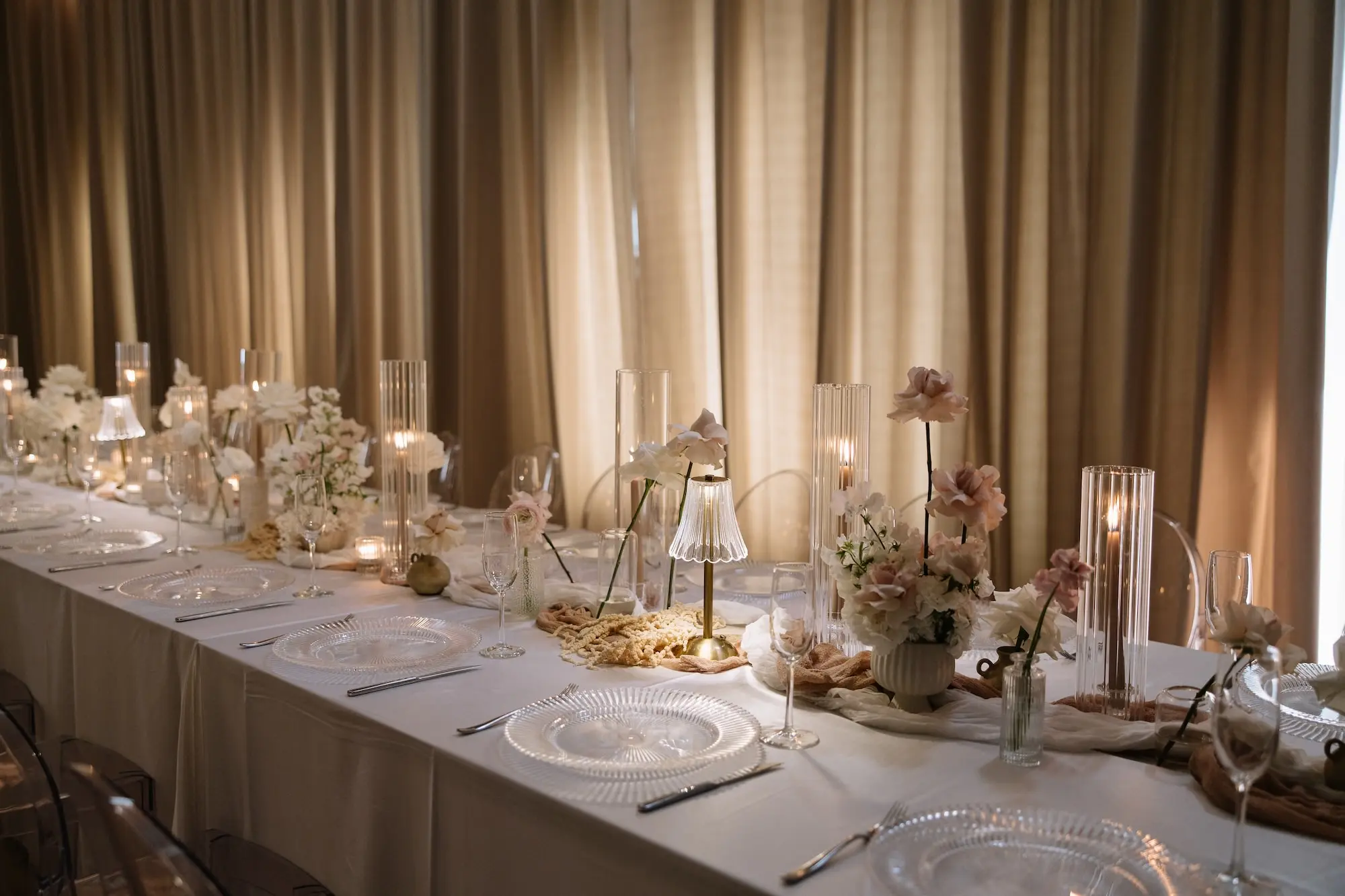 Luxurious Ballroom Wedding Reception | Modern Clear Chairs and White Linens on Long Table Decor Inspiration | Single Stem Centerpieces in Bud Vases with White Flower Arrangement Ideas | Romantic Taper Candles in Vases and Small Gold Table Lamps Decor Inspiration | White Linen Ceiling and Wall Draping Ideas | Tampa Bay Planner EventFull Weddings | Ybor Event Venue Hotel Haya