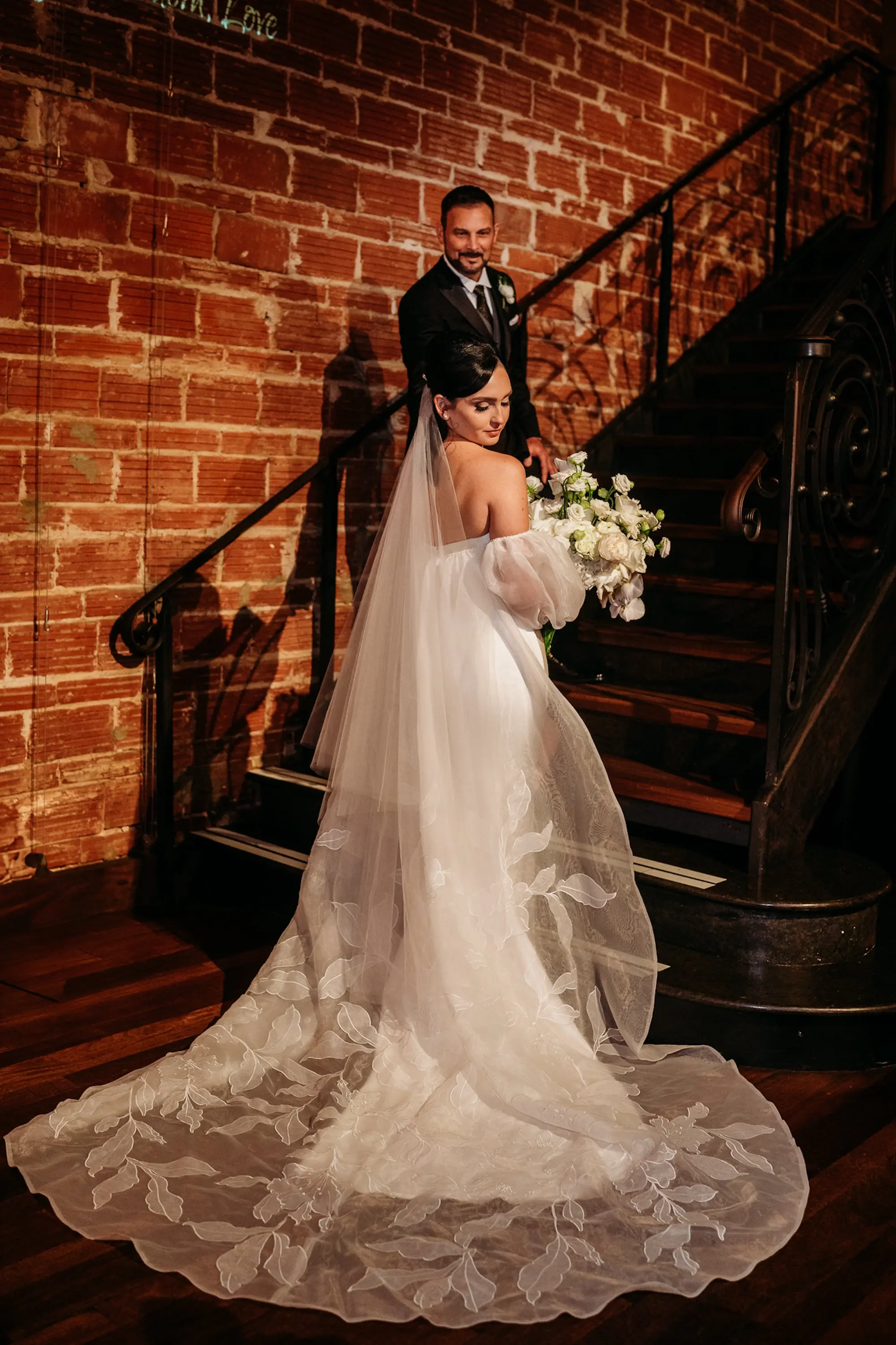 Bride and Groom Staircase Wedding Portrait | White Simple, Elegant Ines Di Santo Wedding Gown with Structured Bodice, Sweetheart Neckline and High Slit Inspiration | Half Up Half Down Bridal Hair Ideas | Chiffon Traditional Veil Inspiration | Custom Floral Detailed Jenny Woo Bridal Cape Ideas | St Pete Hair and Makeup Artist Femme Akoi Beauty Studio | Tampa Bay Photographer Sabrina Autumn Photography
