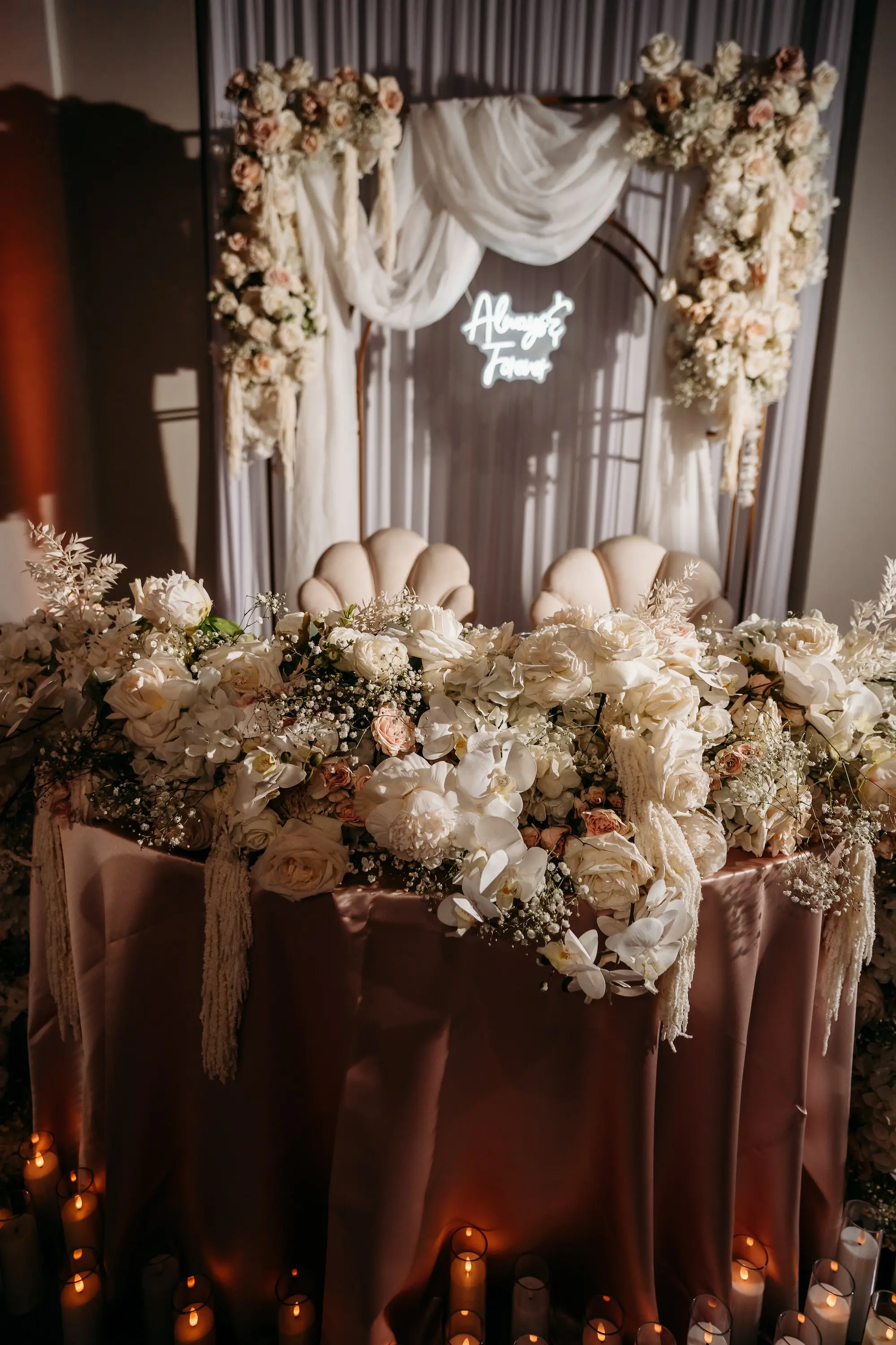 Romantic Blush Pink, White, and Champagne Sweetheart Table with Candles Wedding Reception Decor Inspiration with Draping, Backdrop, and Neon Sign
