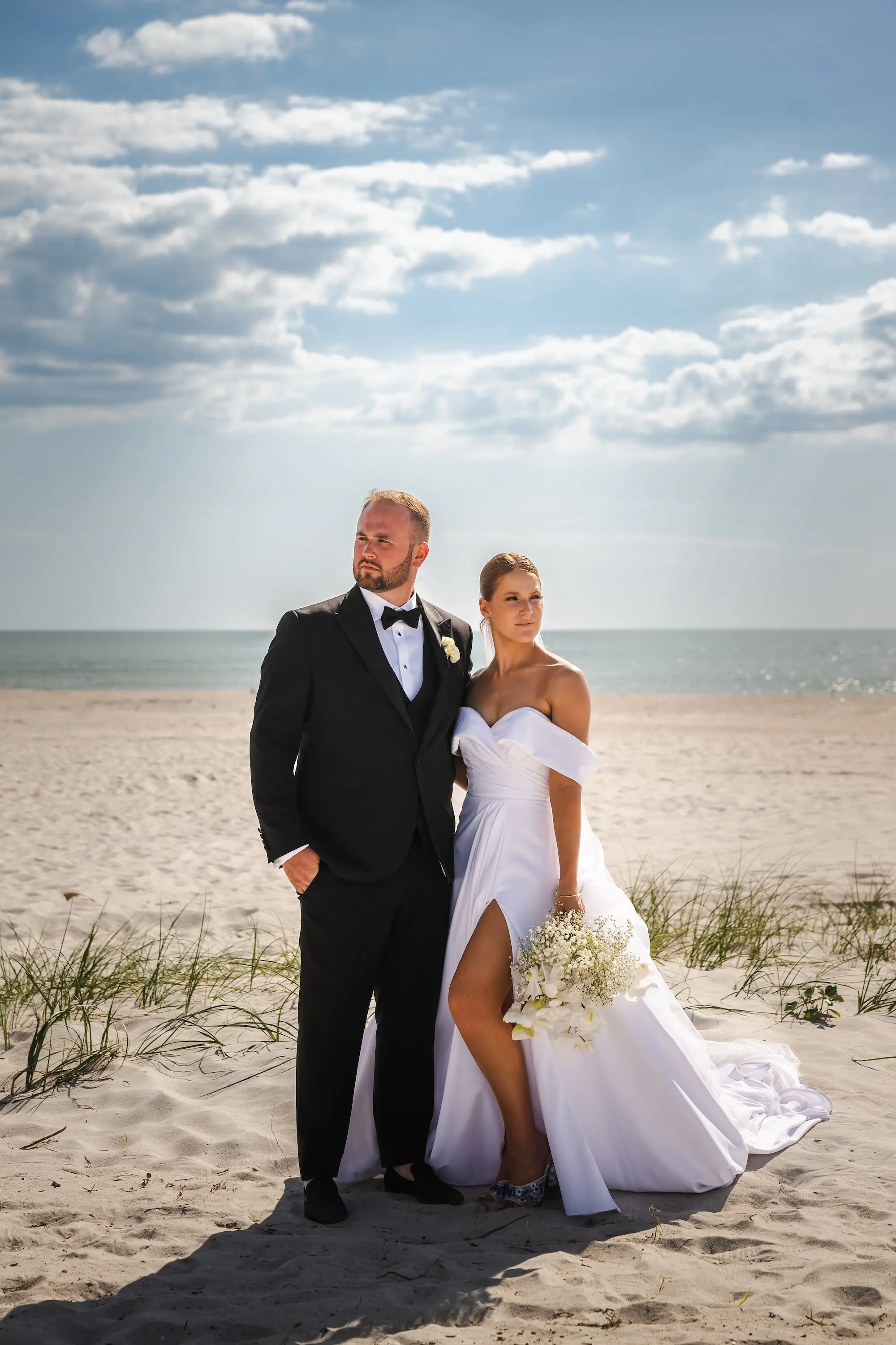 Bride and Groom St Pete Beach Wedding Portrait | White Off-the-Shoulder Wedding Gown with Sweetheart Neckline and High Slit Inspiration | Classic White and Black Groom's Tuxedo Ideas | Classic White Roses, Baby's Breath Bridal Bouquet Inspiration | St Pete Videographer Photographer Iyrus Weddings | Tampa Bay Event Venue TradeWinds Island Resort