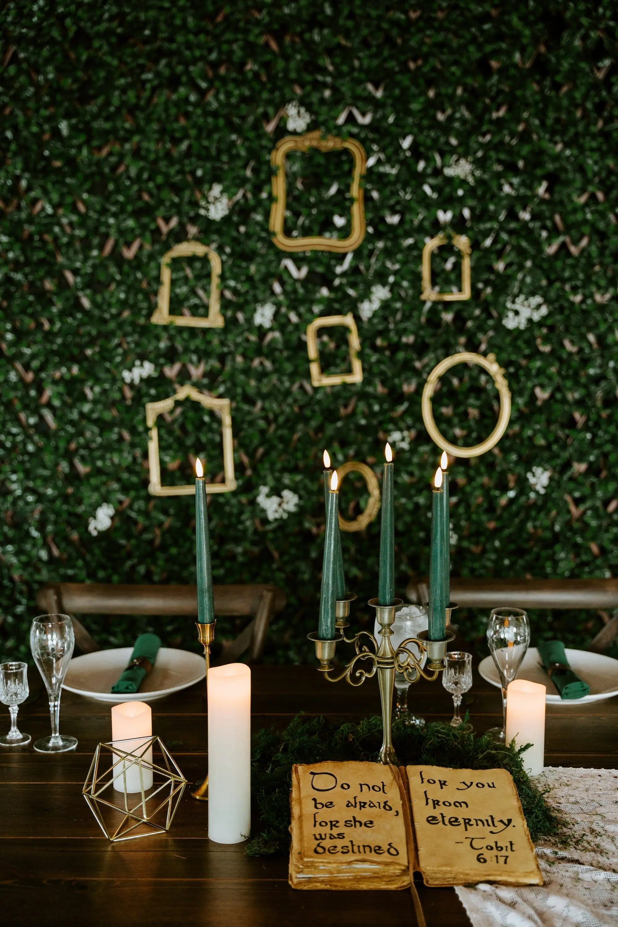 Magical Woodland Fantasy Wooden Sweetheart Table with Green Taper Candles in Gold Candelabra Wedding Reception Decor Inspiration | Green Ivy Decor Wall with Gold Frames Decor Ideas | Gold Accents Table Decor Inspiration
