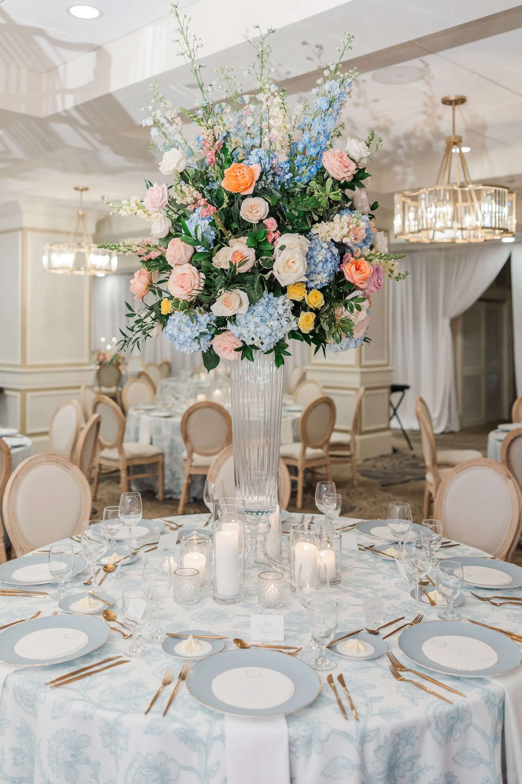Luxurious Spring Garden Party Ballroom Wedding Reception Decor Inspiration | Light Blue Linens with King Louis XIV Chairs Decor Ideas | Tall Glass Pastel Pink, Blue, Peach Roses, Peonies, Hygragendas Flower Arrangement Centerpieces Inspiration | Blue and White China with Gold Rim and Gold Flatware Decor Ideas | Romantic Different Size Candles in Glass Vases Tablescape Decor Inspiration | Clearwater Event Venue Belleair Country Club | Tampa Bay Planner Parties a La Carte | Florist Bruce Wayne Florals