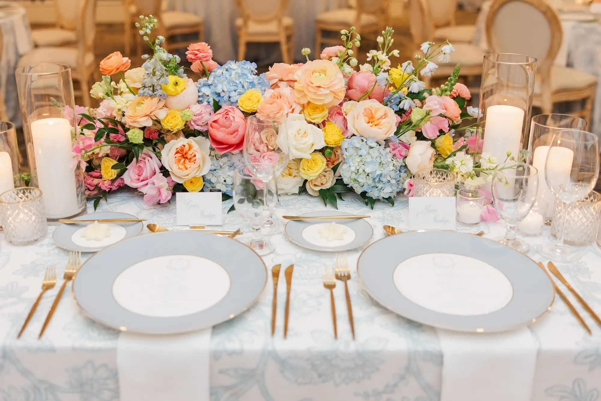 Spring Garden Party Wedding Reception Centerpiece Place Setting Tablescape Decor Ideas | Luxurious Spring Garden Party Ballroom Wedding Reception Decor Inspiration | Blue and White China with Gold Rim and Gold Flatware Decor Ideas | Romantic Different Size Candles in Glass Vases Tablescape Decor Ideas | Pastel Pink, Blue, Peach Roses, Peonies, Hygragendas Flower Arrangement Centerpieces Inspiration | Clearwater Event Venue Belleair Country Club | Tampa Bay Planner Parties a La Carte | Florist Bruce Wayne Florals
